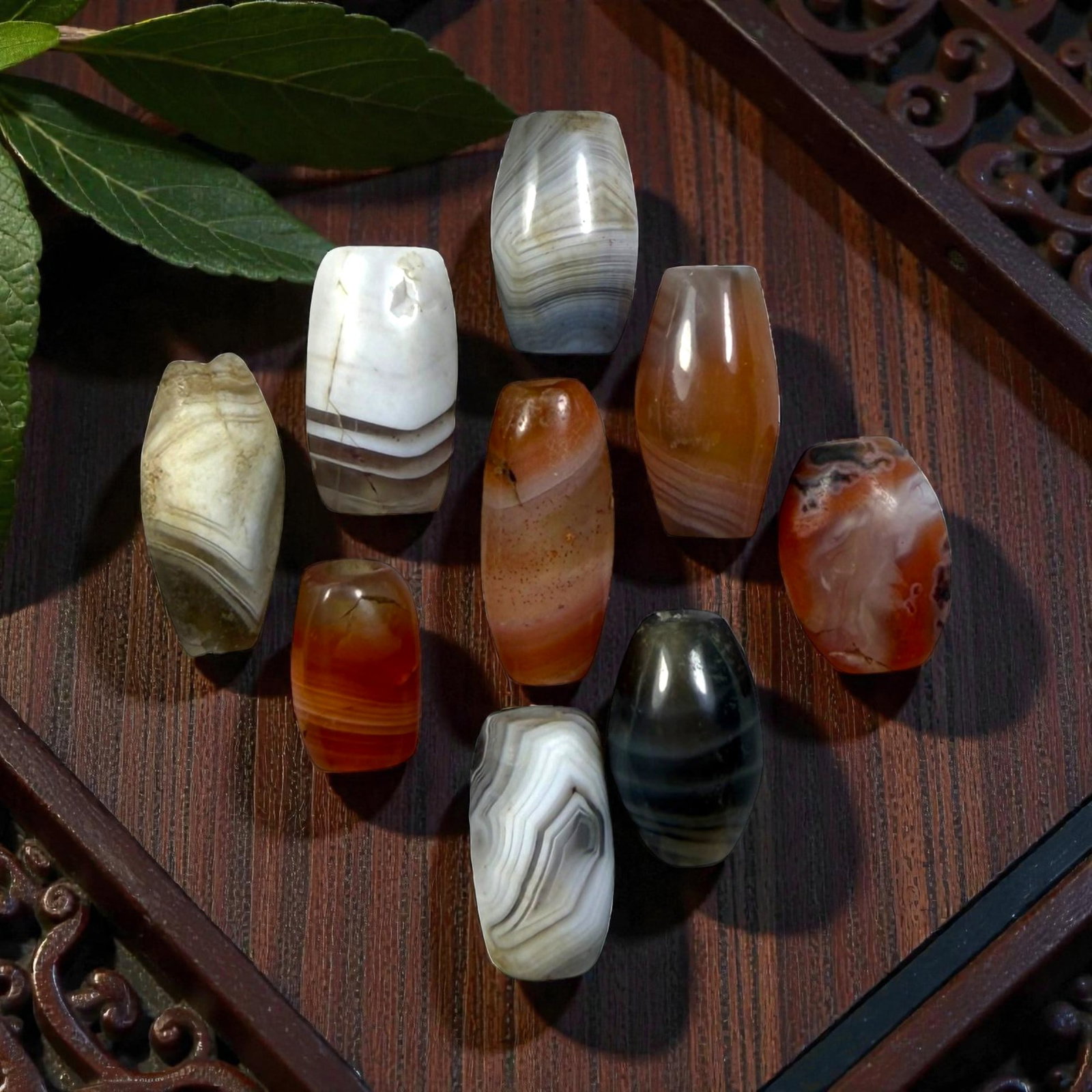 A Lot of 9 Himalayan Banded Agate Beads, Ancient to Antique Period, 34YD: Comprising lot of barrel and ovoid beads, each carved from banded agate with natural tonal variations, many displaying characteristic concentric, linear, and dendritic patterns. The surfaces exhibit s