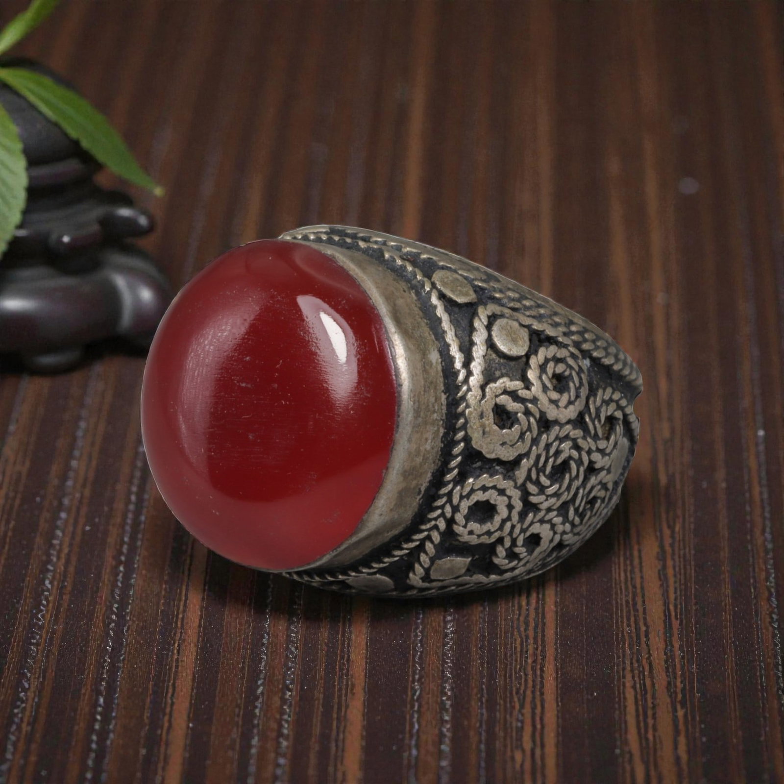 Antique Central Asian Silver and Carnelian Tribal Ring, 19th-Early 20th Century, 61AJ: The ring is set with a large, smooth cabochon carnelian stone. The silver mount is decorated with pseudo-filigree wirework and applied coiled motifs, set against a darkened background. The metal exhib