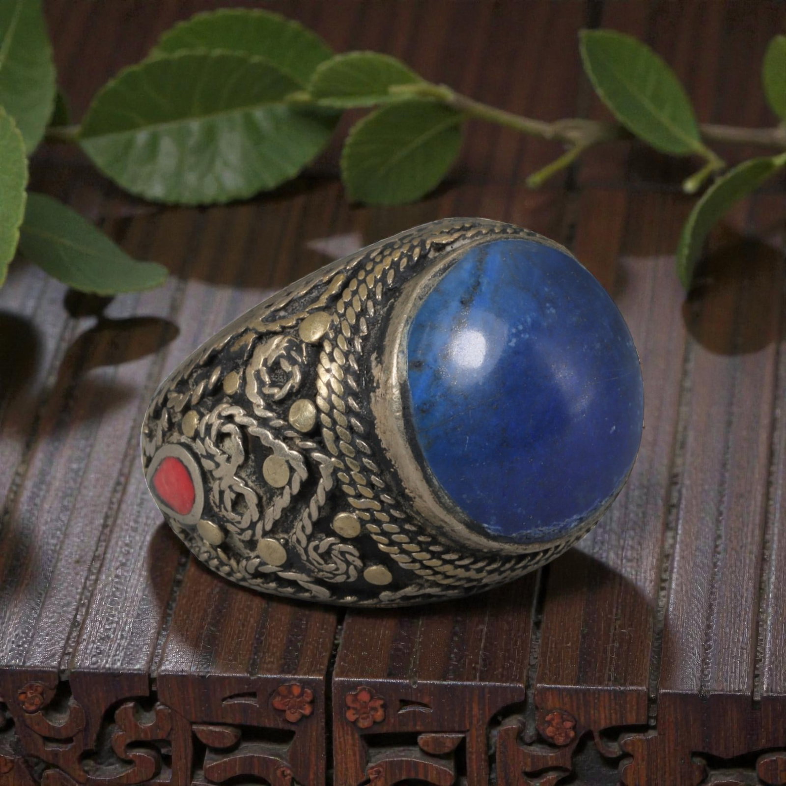 Antique Central Asian Silver and Lapis Lazuli Tribal Ring, 19th-Early 20th Century, 56AJ: The ring is set with a large, smooth cabochon lapis lazuli stone, displaying natural tonal variations within its deep blue matrix. The silver mount is decorated with pseudo-filigree wirework, applied 