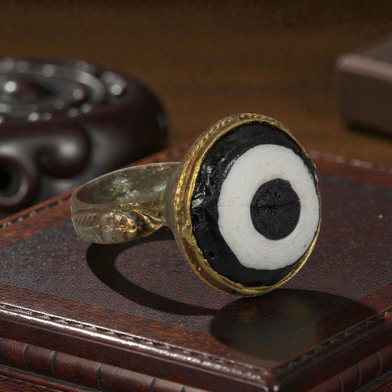 Antique Qajar Dynasty Gilt Evil Eye Ring, US Size 8, 41AJ: A gilt-metal ring of the Qajar period, US ring size 8, featuring a large domed evil-eye glass inlay with concentric black, white, and dark central layers. The bezel is decorated with embossed foliate 