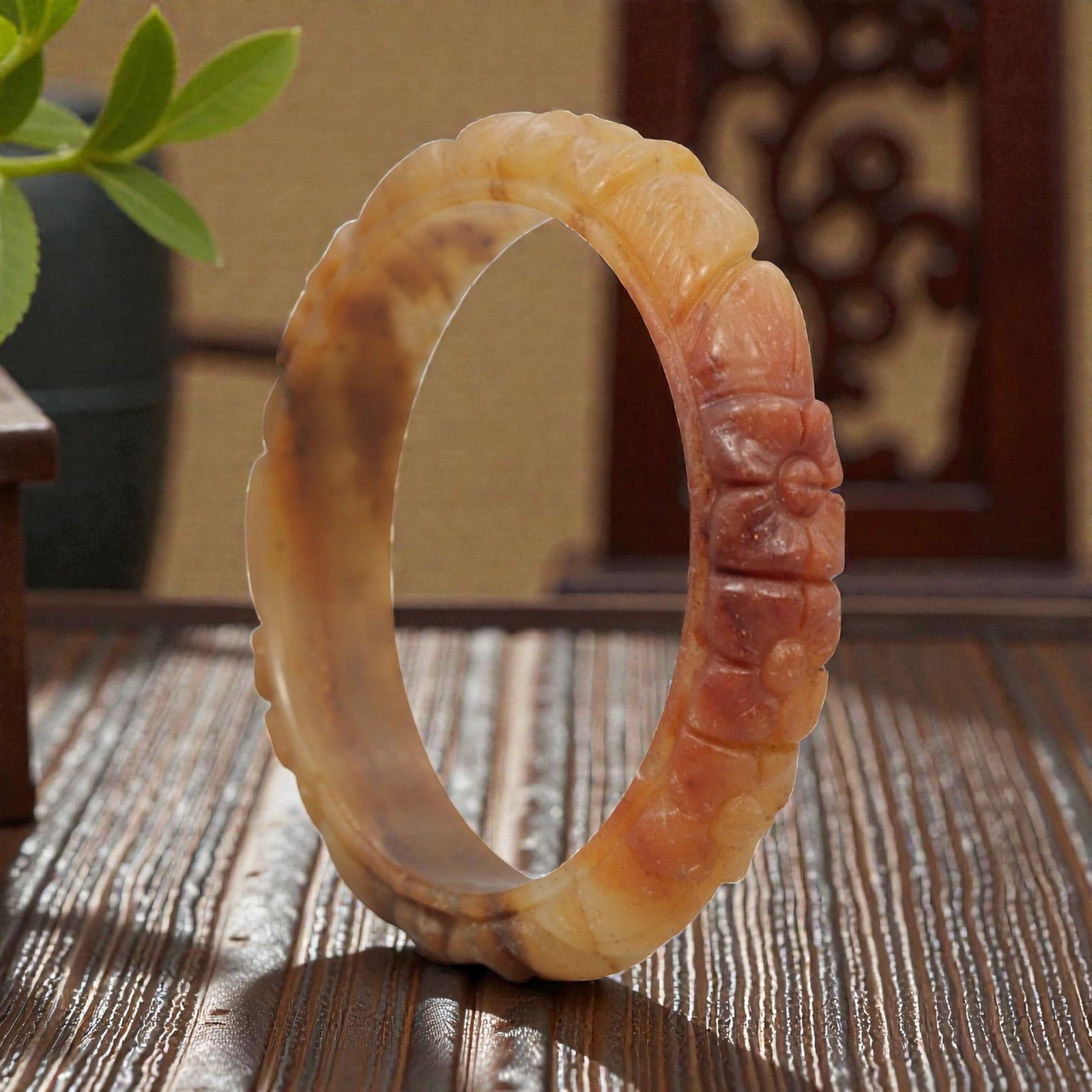 A Chinese Carved Jadeite Jade Bangle Bracelet, 20th Century, 43ZL: A fine jadeite bangle of flattened circular form, masterfully carved in relief with a continuous band of floral blossoms and scrolling foliate motifs. The stone exhibits a striking variegated palette,