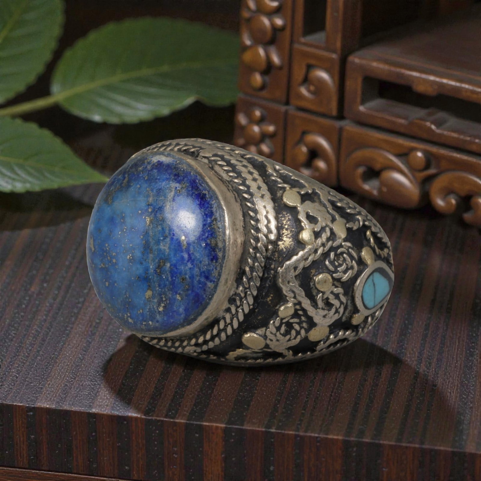 Antique Central Asian Silver and Lapis Lazuli Tribal Ring, 19th-Early 20th Century, 62AJ: The ring is set with a large, smooth cabochon lapis lazuli stone, displaying characteristic pyrite inclusions within its deep blue matrix. The silver mount is decorated with pseudo-filigree wirework, 