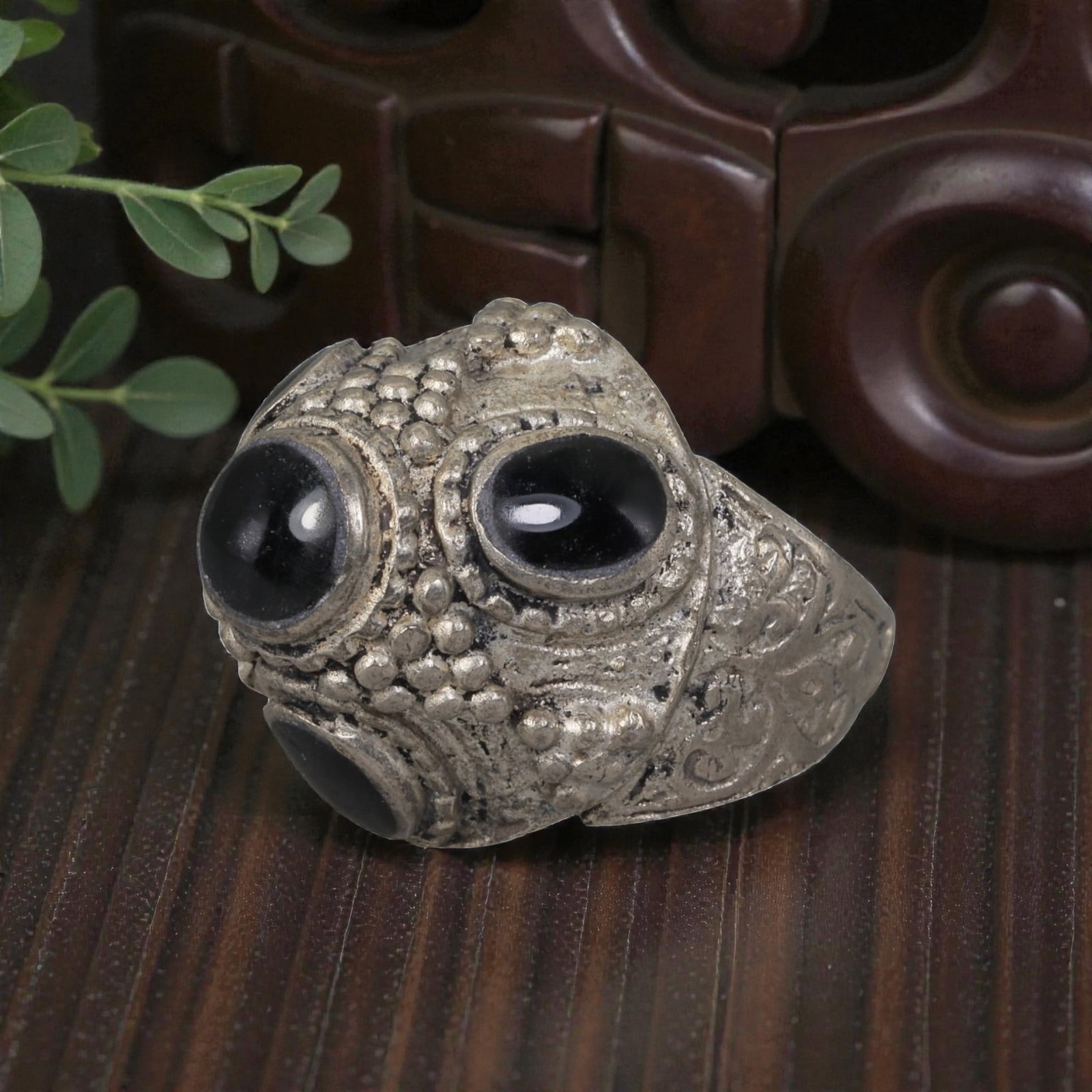 A Middle Eastern Silver Plated Multi-Stone Onyx Ring, Late 19th-Early 20th Century, 34AK: The ring features multiple round and oval cabochon onyx stones set within an ornate domed bezel decorated with raised granulation. The bezel and shoulders are engraved with scrolling foliate motifs. T