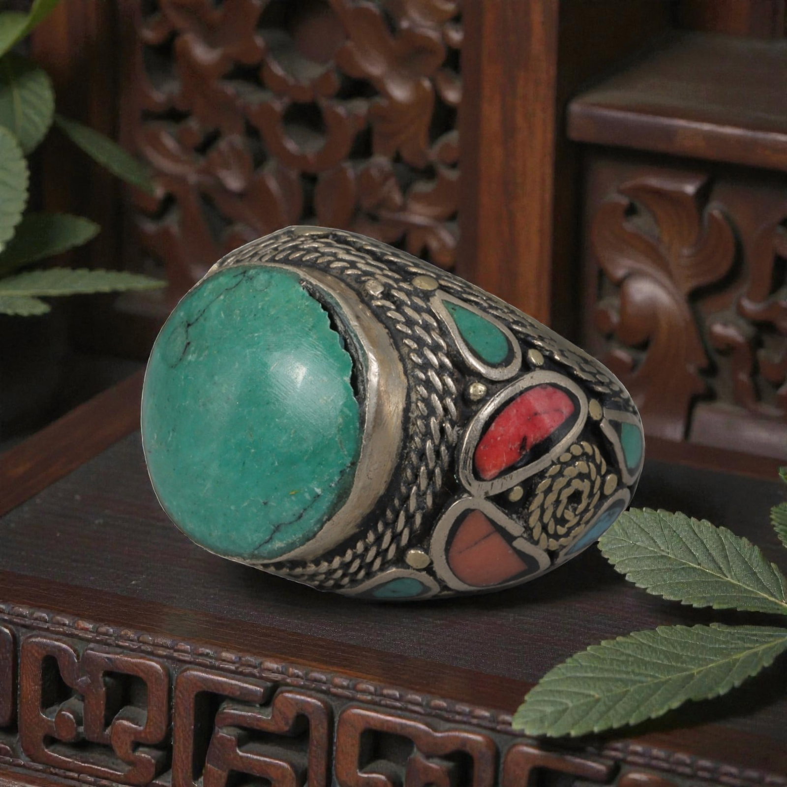 Antique Central Asian Silver and Turquoise Tribal Ring, 19th-Early 20th Century, 70AJ: The ring is set with a large cabochon turquoise stone, displaying natural matrix inclusions and surface cracks within its green-blue matrix. The silver mount is decorated with pseudo-filigree scale-pa