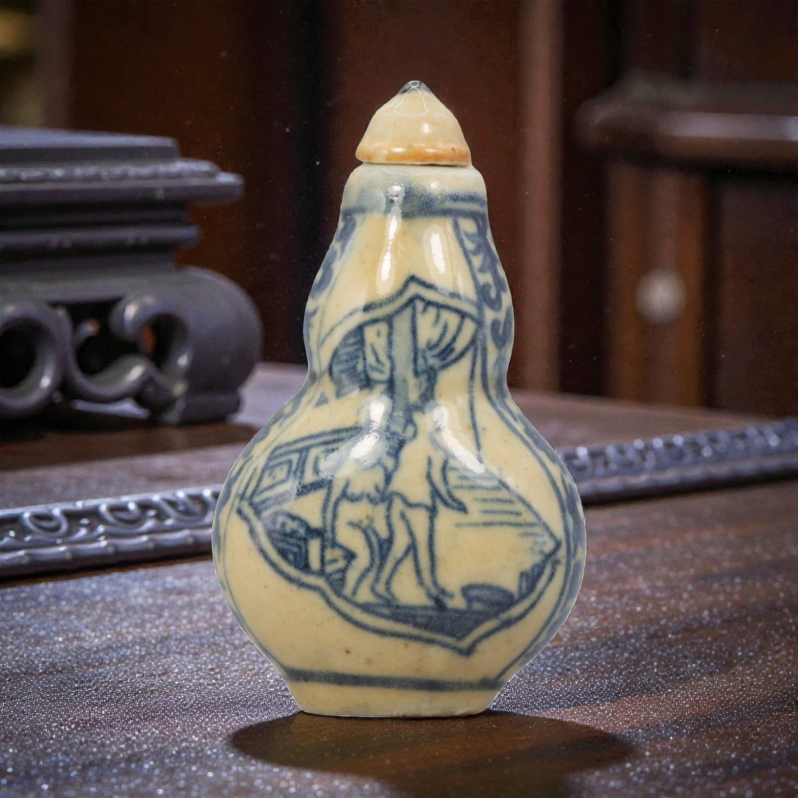 A Chinese Porcelain Double-Gourd Snuff Bottle, 20th Century, 1YD: Crafted from porcelain with a pale cream glaze and decorated in underglaze blue, the snuff bottle is formed in a double-gourd shape, with a narrow upper bulb, a wider lower bulb, and a short neck fitt