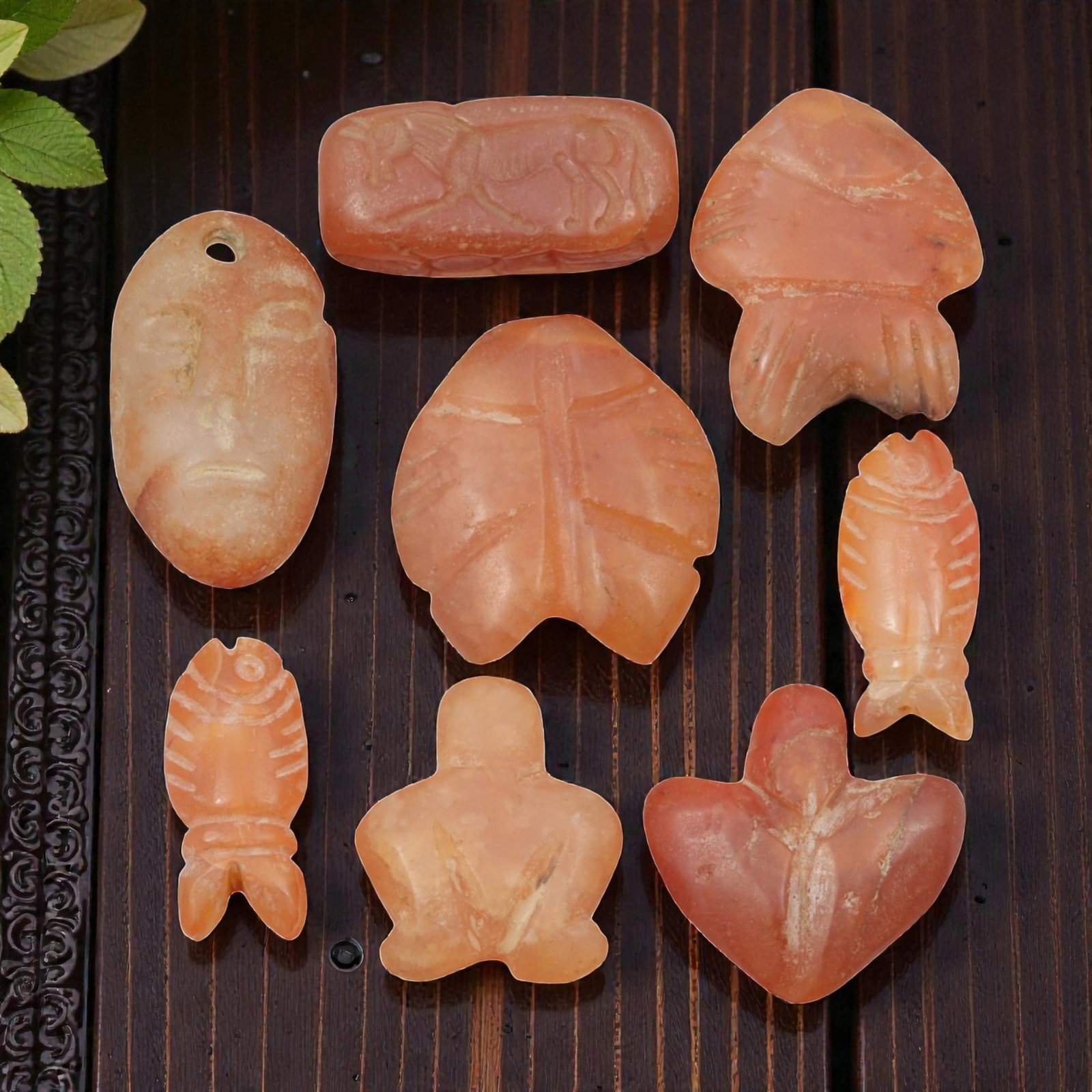 Lot of 8 Ancient Coptic Egyptian Carnelian Amulets, Circa Roman to Coptic Era, 60WT: Carved from carnelian in warm orange-red hues, the group consists of eight amulets of varying forms. The set includes stylized fish, leaf-shaped pendants, a human face pendant with suspension hole, a 