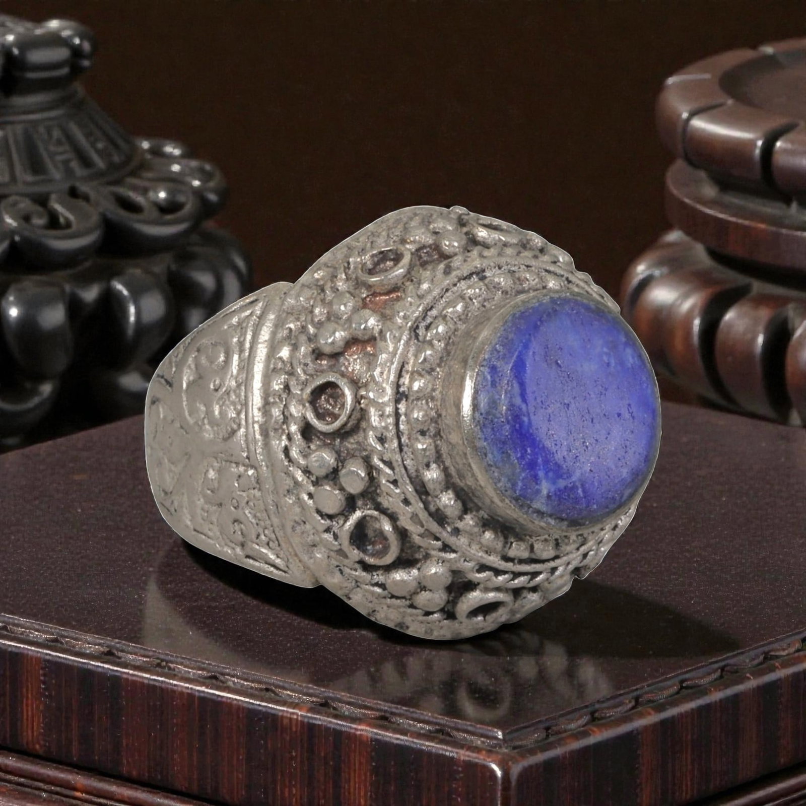 A Middle Eastern Silver Plated Lapis Lazuli Ring, Late 19th-Early 20th Century, 8AK: The ring is centered with a round cabochon lapis lazuli stone exhibiting deep blue color and natural pyrite flecks, set within an ornate domed bezel decorated with beaded granulation, twisted wirework