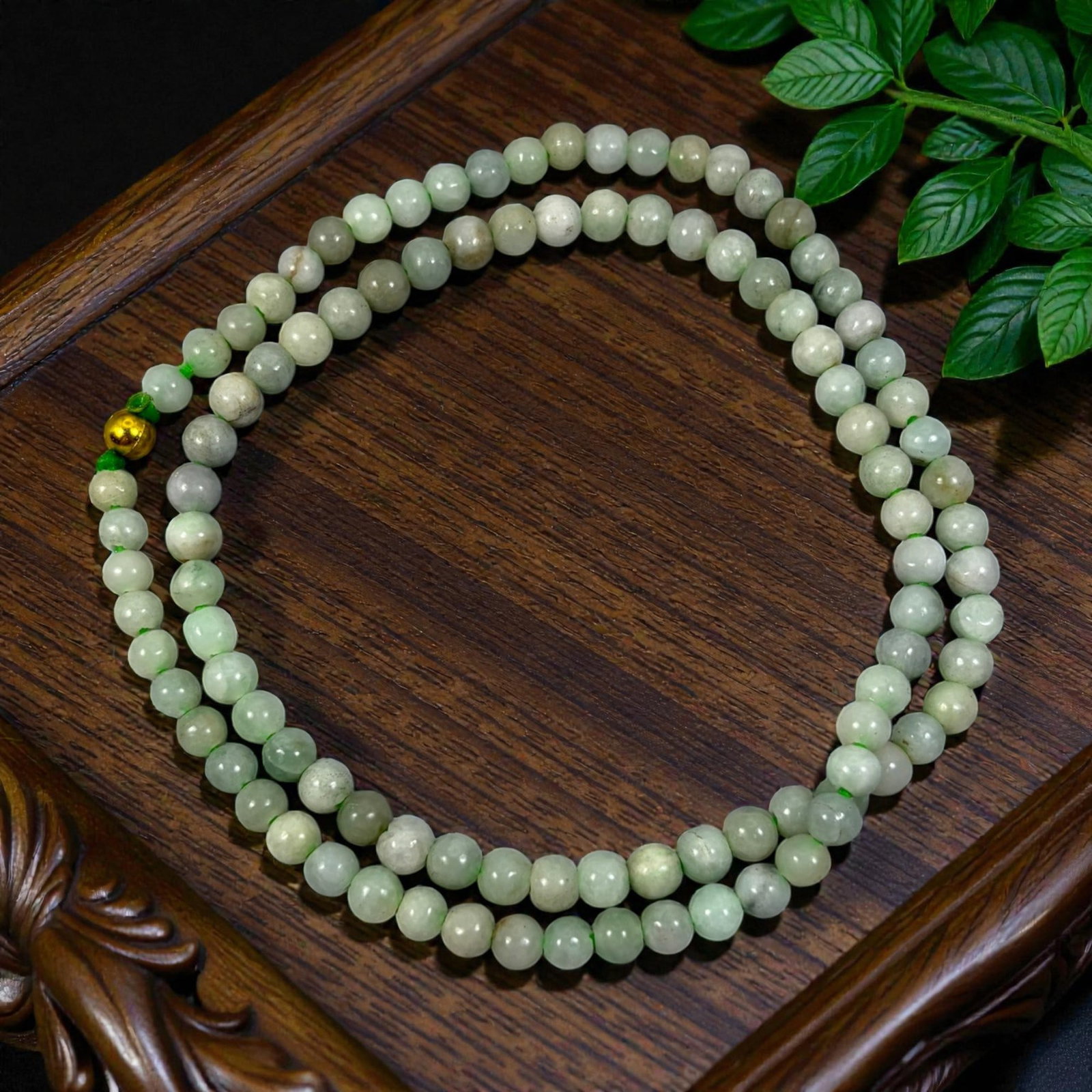 Chinese Jadeite Jade Bead Necklace, 20th Century, 97XE: A continuous strand of polished jadeite beads, each of uniform spherical form, with subtle variations in pale green and white hues, characteristic of natural stone inclusions and patination. The beads