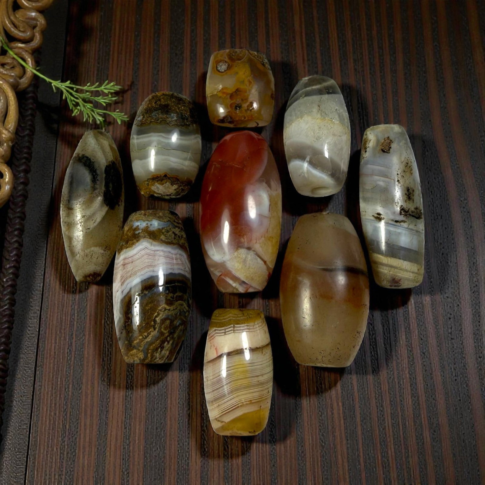 A Lot of 9 Himalayan Banded Agate Beads, Ancient to Antique Period, 47AN: Comprising lot of barrel and ovoid beads, each carved from banded agate with natural tonal variations, many displaying characteristic concentric, linear, and dendritic patterns. The surfaces exhibit s