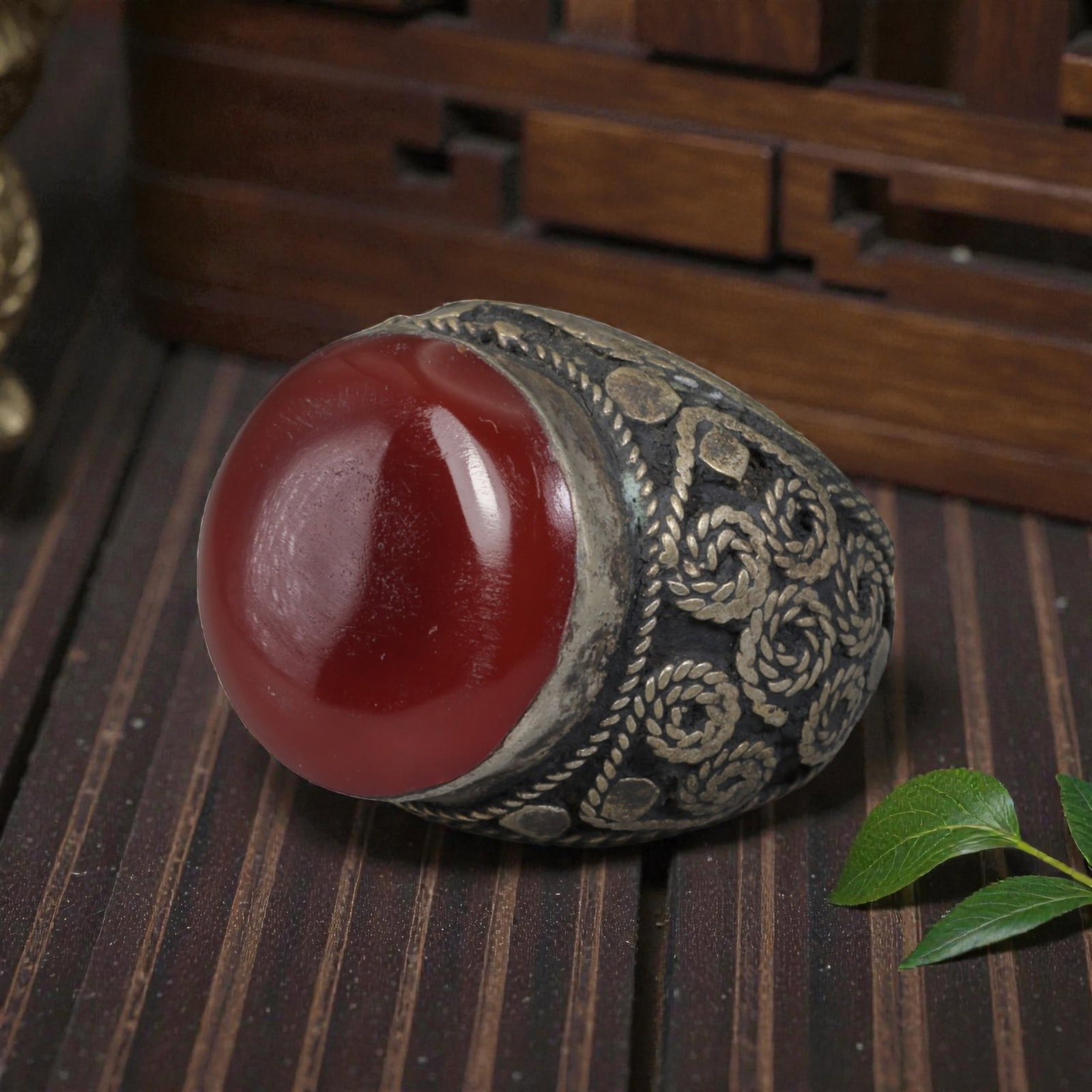 Antique Central Asian Silver and Carnelian Tribal Ring, 19th-Early 20th Century, 60AJ: The ring is set with a large, smooth cabochon carnelian stone, secured within a silver mount. The mount is decorated with pseudo-filigree wirework and applied coiled motifs, set against a darkened bac