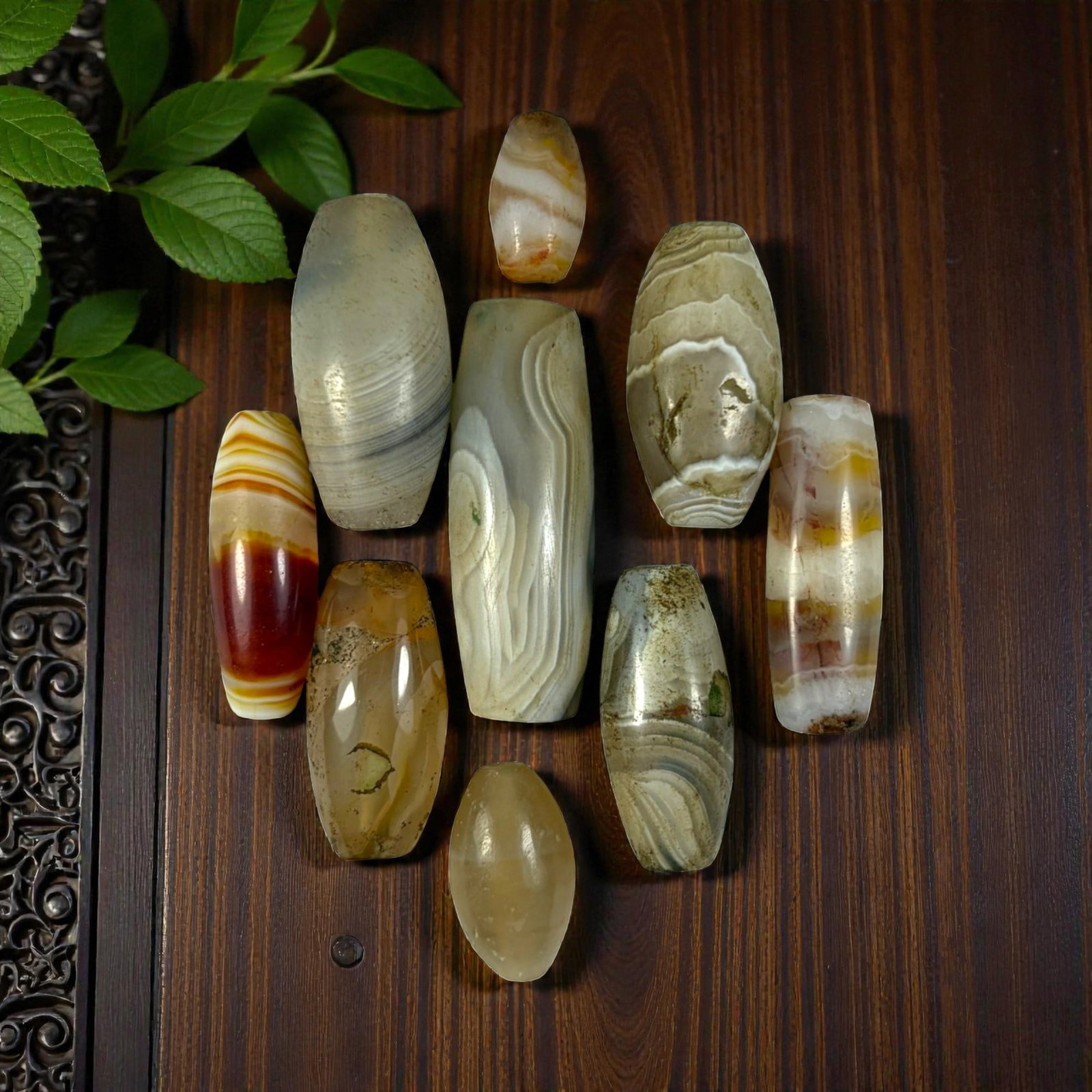A Lot of 9 Himalayan Banded Agate Beads, Ancient to Antique Period, 25YD: Comprising lot of barrel and ovoid beads, each carved from banded agate with natural tonal variations, many displaying characteristic concentric, linear, and dendritic patterns. The surfaces exhibit s