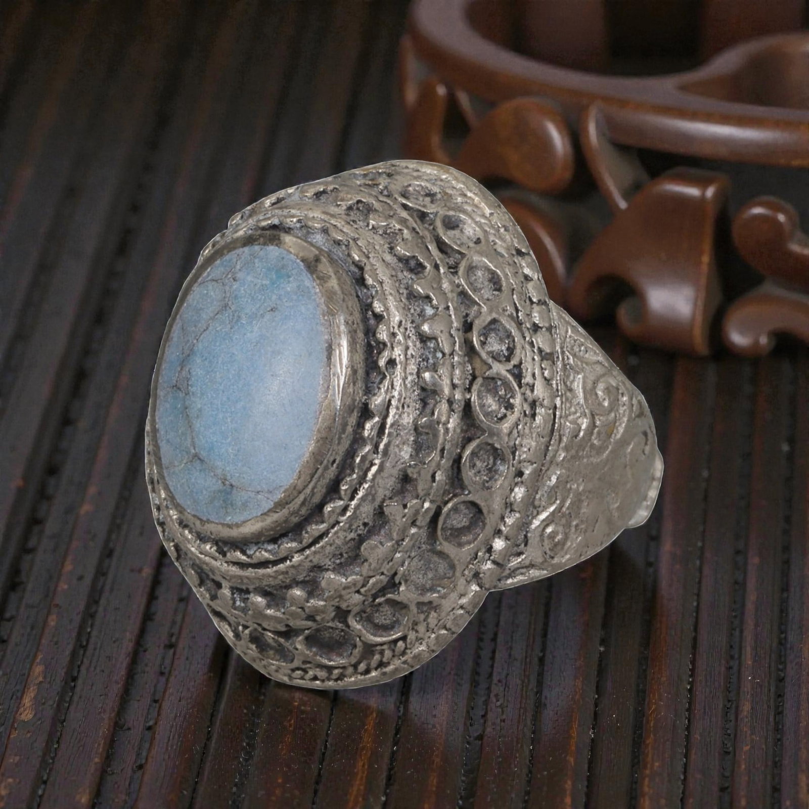 A Middle Eastern Silver Plated Turquoise Ring, Late 19th-Early 20th Century, 40AK: The ring is centered with an oval cabochon turquoise stone exhibiting light blue color and natural surface veining, set within a domed bezel decorated with openwork circular patterns and floral motifs