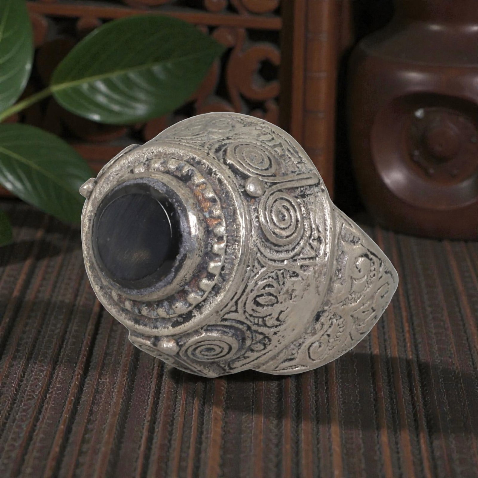 A Middle Eastern Silver Plated Onyx Ring, Late 19th-Early 20th Century, 9AK: The ring is centered with a round cabochon onyx stone set within a domed bezel featuring a raised beaded border. The bezel and shoulders are engraved with stylized spiral and foliate motifs. The silve