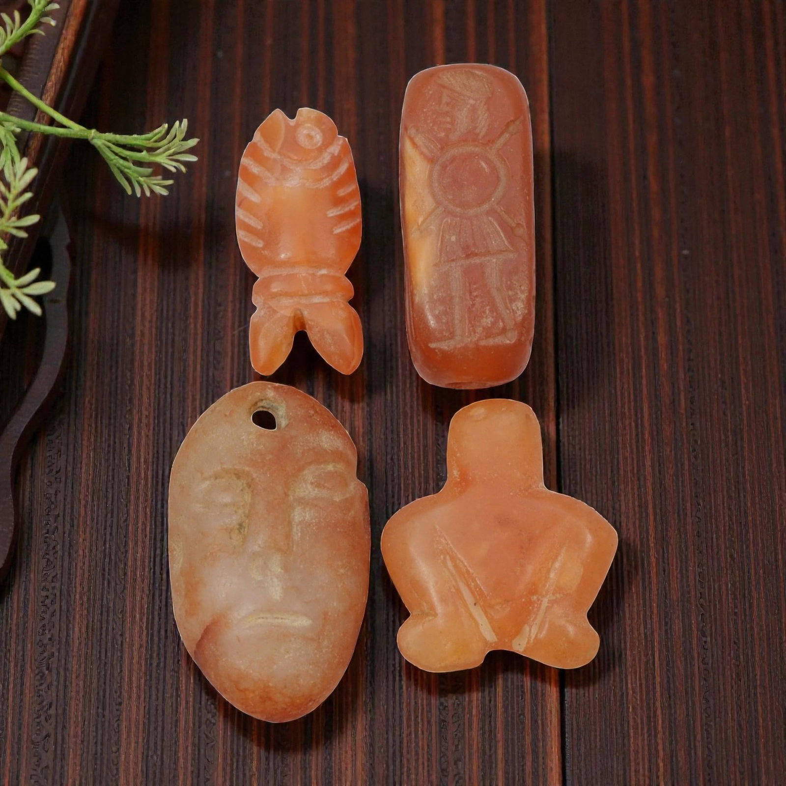 Lot of 4 Coptic Egyptian Carnelian Amulets, Circa Roman to Coptic Era, 18WS: The group comprises four carnelian amulets, each carved from orange-red stone with natural translucency and surface patina. The forms include a stylized fish, a rectangular seal bead incised with a st