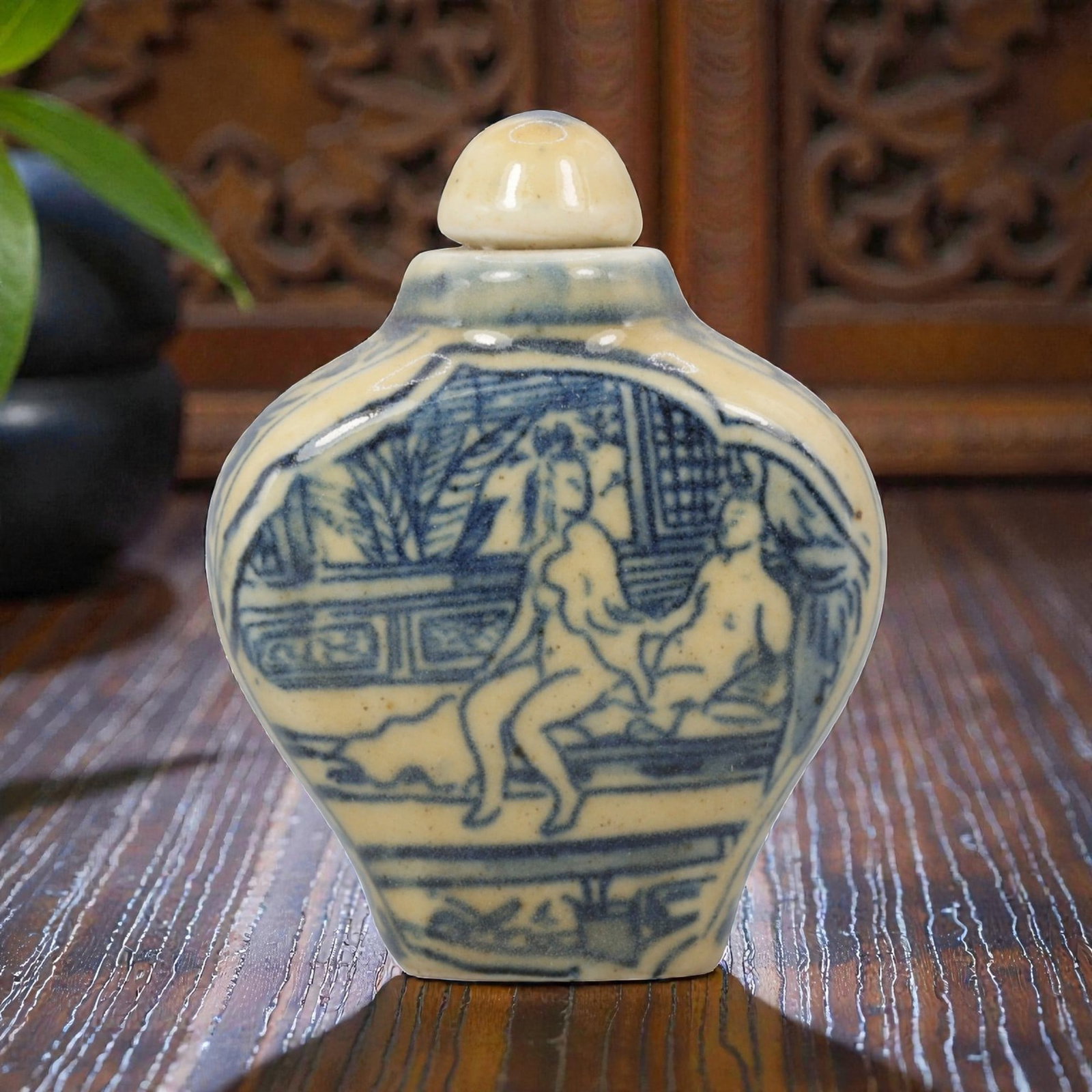 A Chinese Porcelain Snuff Bottle, 20th Century, 57BE: Crafted from porcelain with a pale cream glaze and decorated in underglaze blue, the snuff bottle features a flattened, faceted globular body, a short cylindrical neck, and a domed stopper. The main s