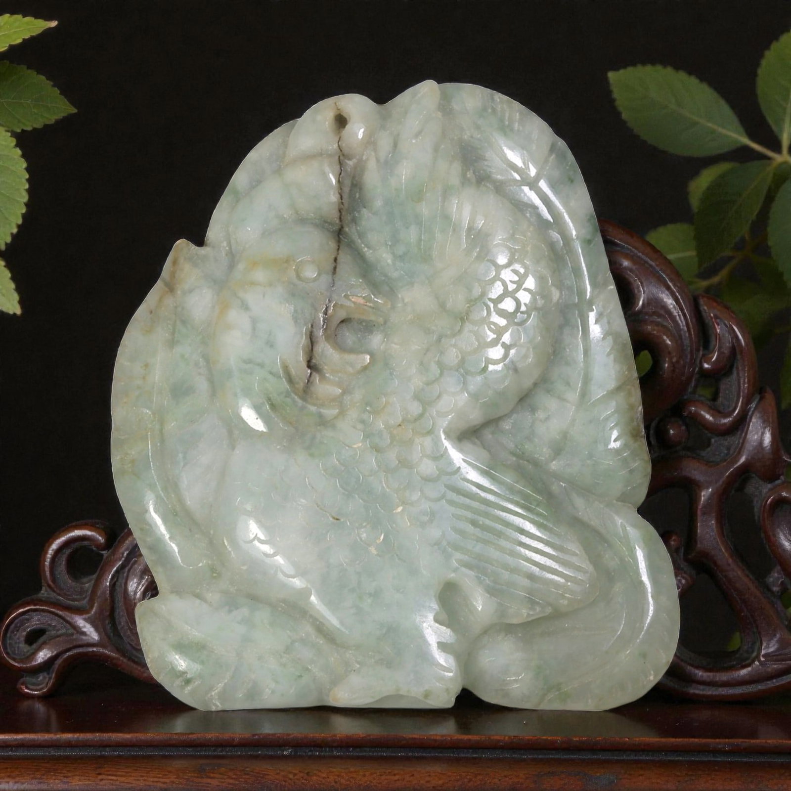 An Antique Oriental Chinese Jadeite Jade Bird Pendant, 51AG: Carved from pale greenish-white jadeite with natural mottling and faint green inclusions, the pendant depicts a stylized bird with detailed scaled plumage, incised wing feathers, and a defined eye and