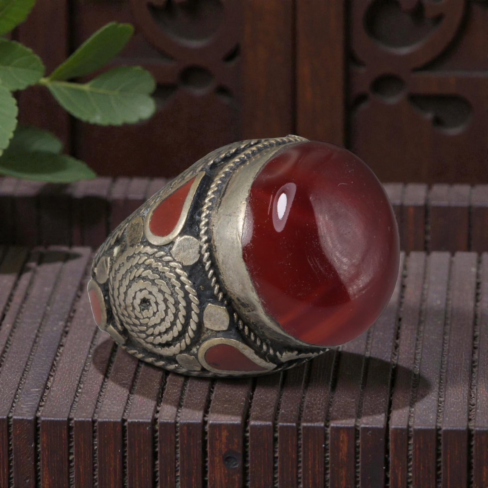 Antique Central Asian Silver and Carnelian Tribal Ring, 19th-Early 20th Century, 68AJ: The ring is set with a large, smooth cabochon carnelian stone, displaying natural banding within its deep red matrix. The silver mount is decorated with pseudo-filigree wirework, a spiral motif, and i