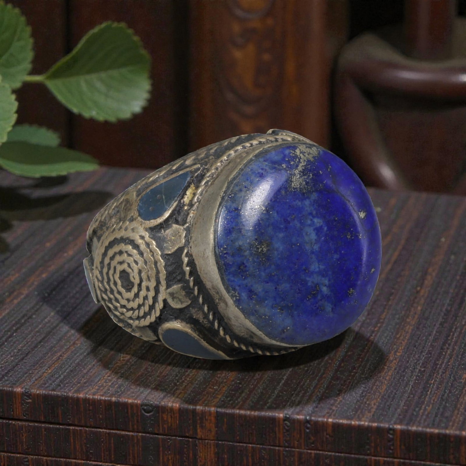 Antique Central Asian Silver and Lapis Lazuli Tribal Ring, 19th-Early 20th Century, 64AJ: The ring is set with a large, smooth cabochon lapis lazuli stone, displaying characteristic pyrite inclusions within its deep blue matrix. The silver mount is decorated with pseudo-filigree wirework, 