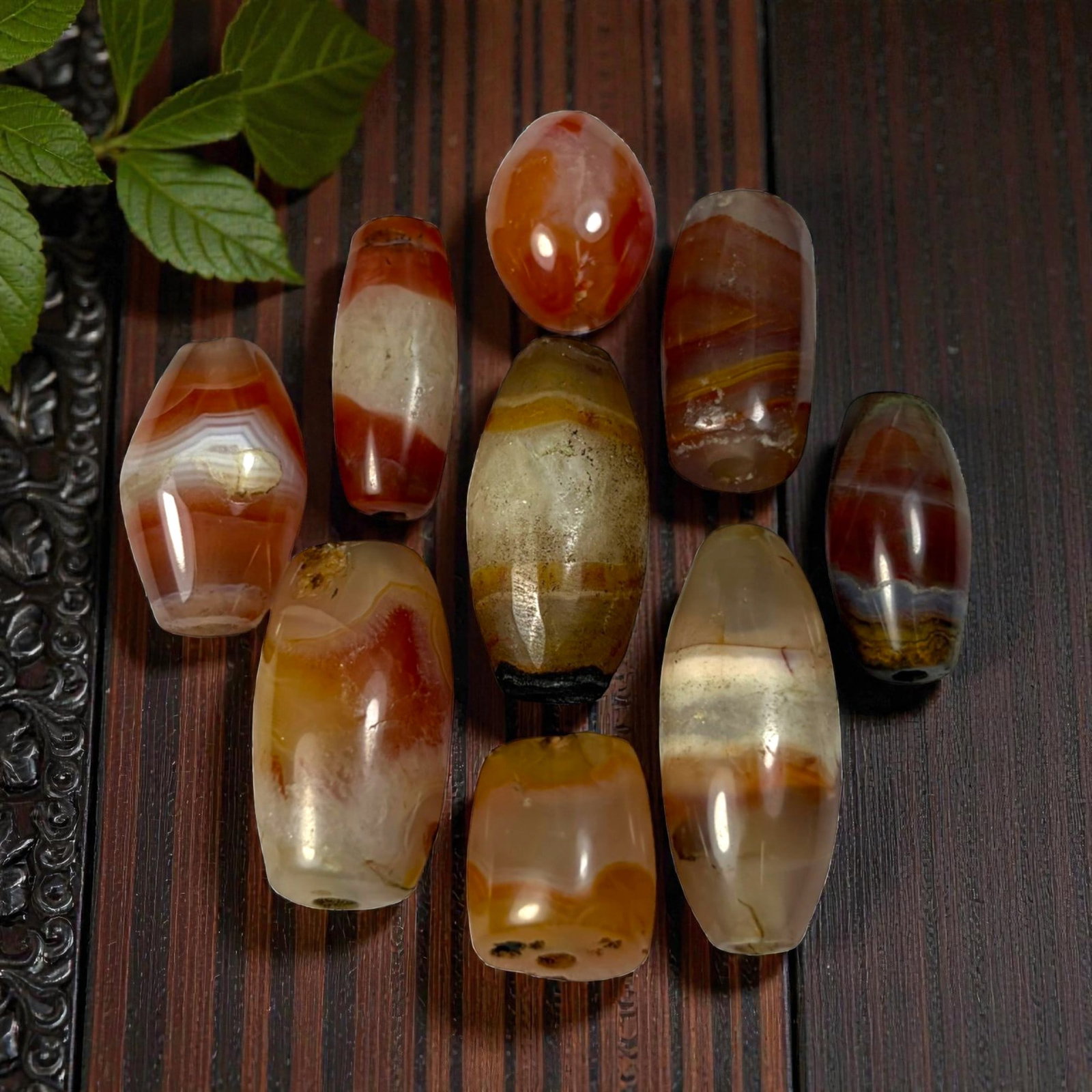 A Lot of 9 Himalayan Banded Agate Beads, Ancient to Antique Period, 44AN: Comprising lot of barrel and ovoid beads, each carved from banded agate with natural tonal variations, many displaying characteristic concentric, linear, and dendritic patterns. The surfaces exhibit s