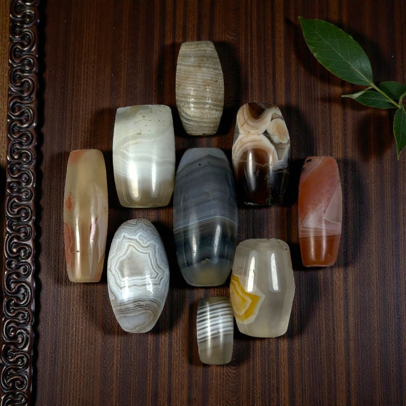 A Lot of 9 Himalayan Banded Agate Beads, Ancient to Antique Period, 31YD: Comprising lot of barrel and ovoid beads, each carved from banded agate with natural tonal variations, many displaying characteristic concentric, linear, and dendritic patterns. The surfaces exhibit s