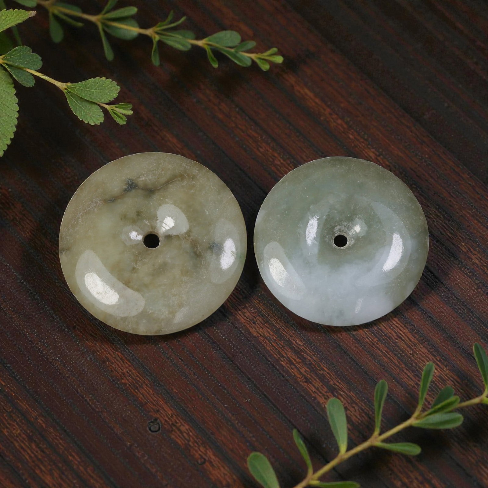 Lot of 2 Antique Oriental Chinese Jadeite Jade Bi Disc Pendants, 26AG: The lot comprises two jadeite jade bi disc pendants. The left disc is carved from mottled olive-green jadeite with natural dark inclusions and cloudy patterning. The right disc is crafted from light g