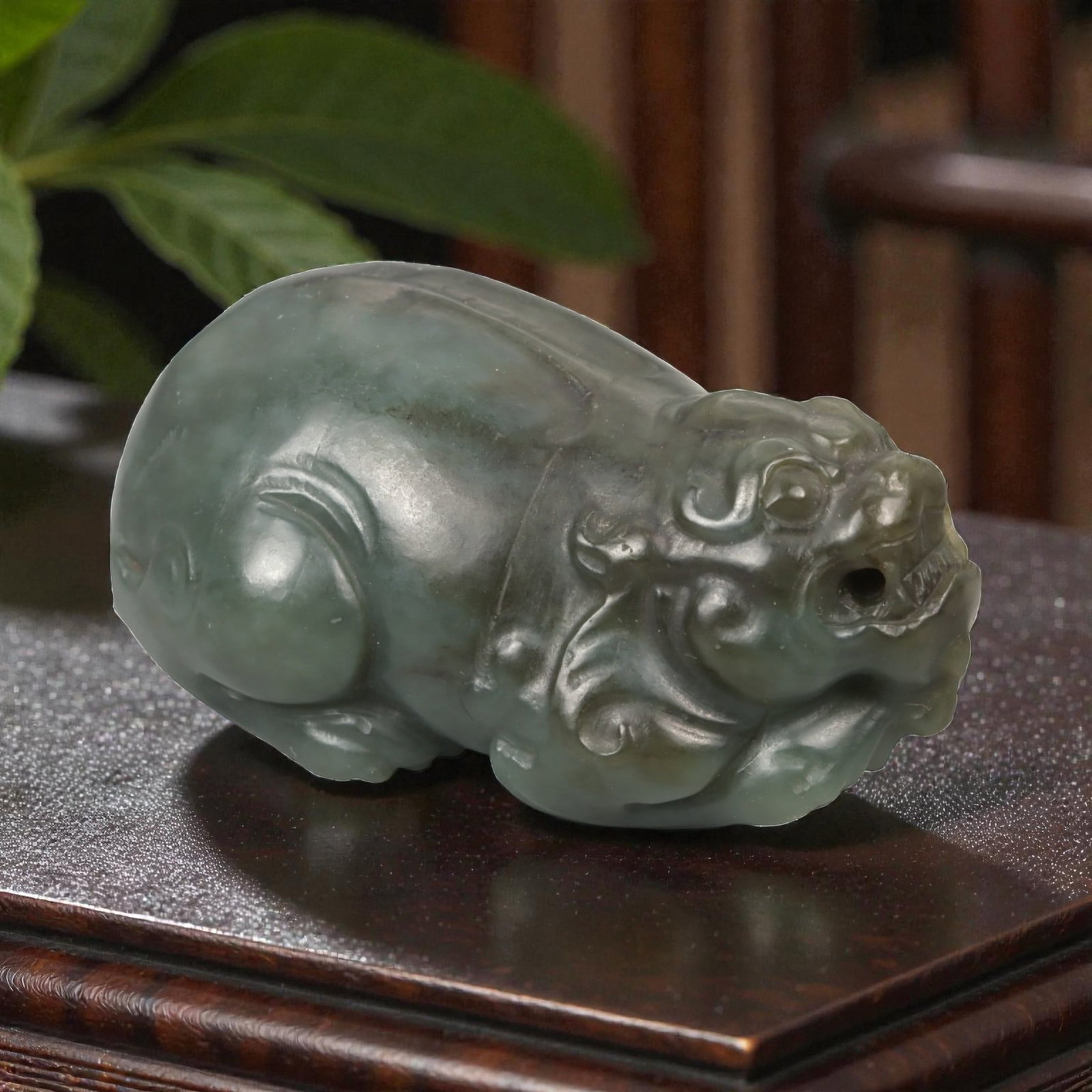 A Chinese Nephrite Jade Pixiu Figure, 20th Century, 66YA: Carved from green nephrite jade with areas of darker saturation and soft translucency, the figure represents pixiu, the mythical beast associated with protection and the attraction of wealth. The crea
