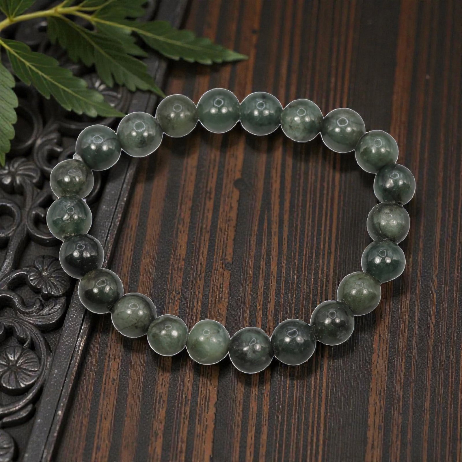 A Chinese Jadeite Jade Bead Bracelet, 20th Century, 57ZK: Composed of a single strand of spherical jadeite jade beads forming a circular bracelet. The beads display natural tonal variation from pale green to deep green, with visible internal mineral inclusio