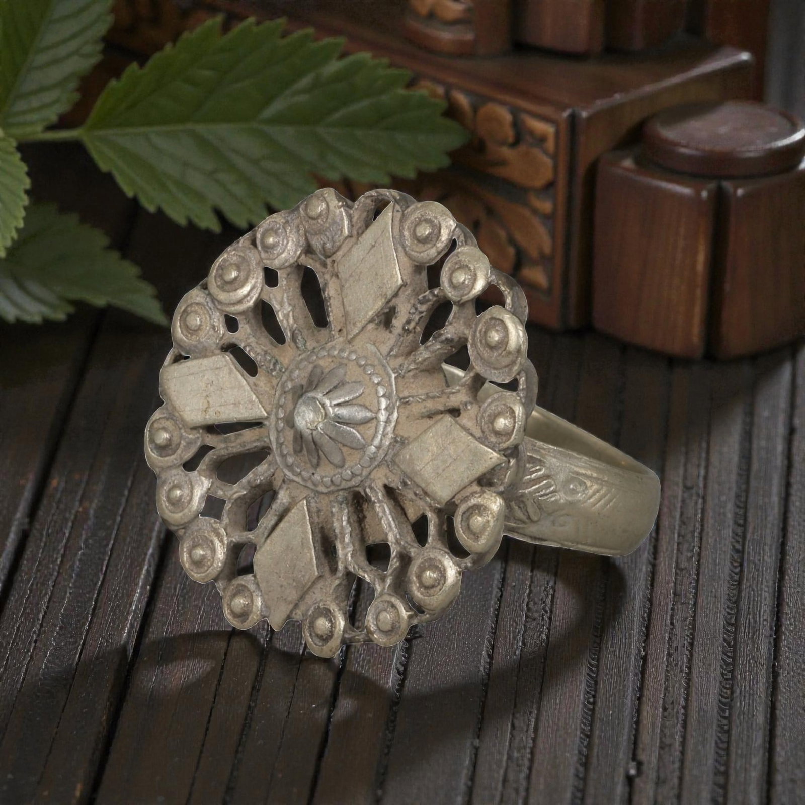A Berber Silver Openwork Floral Motif Ring, Late 19th-Early 20th Century, 41AK: Crafted from silver, featuring a rounded band with subtle incised geometric detailing. The circular bezel displays an openwork design centered on a floral motif, surrounded by radiating elements and a