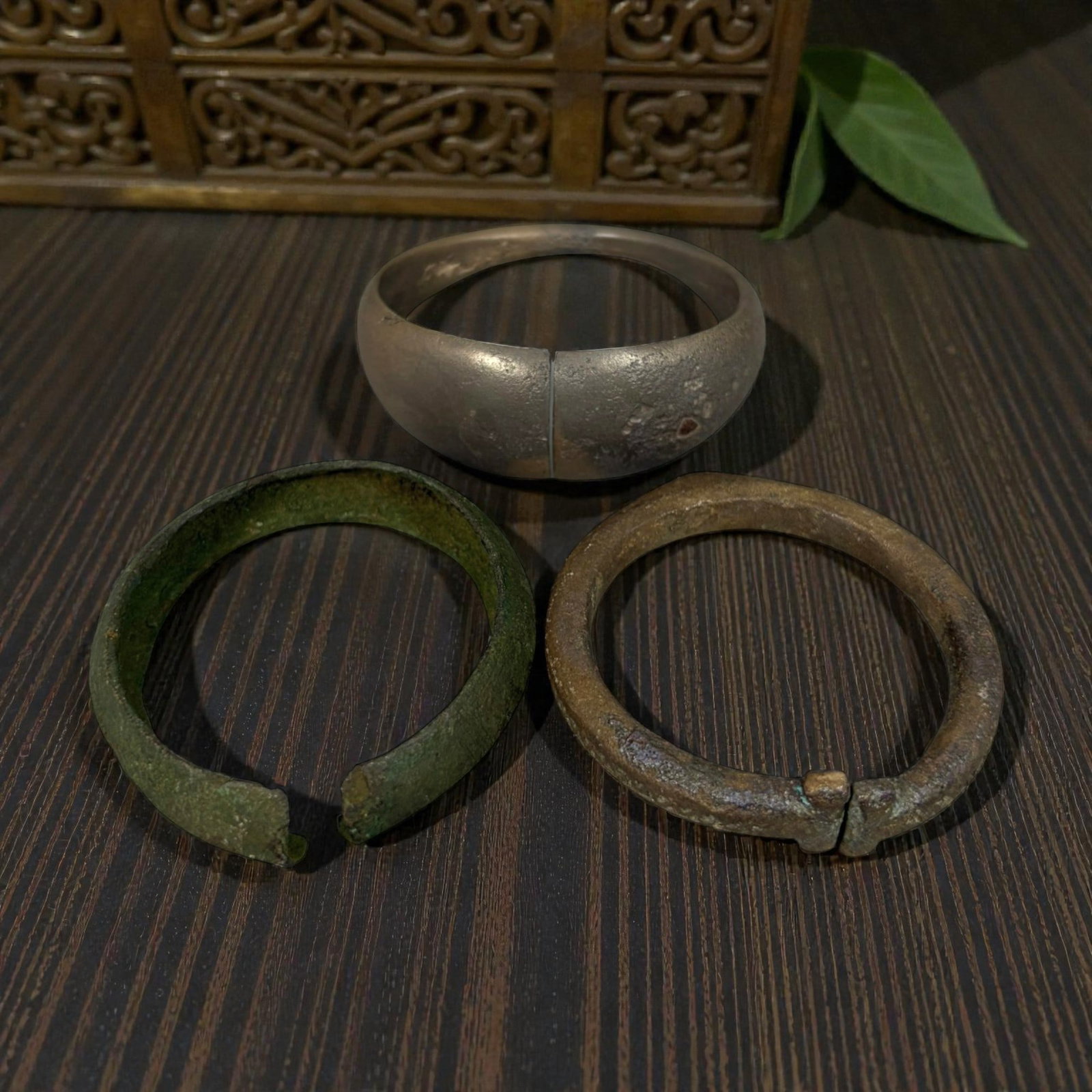 Lot of 3 Roman Bronze Bracelets, Circa 1st-4th Century CE, 88AG: A group of three bracelets crafted from bronze, representing varied Roman-period forms. The top example is a wide, penannular (open) cuff with a smooth, silvery-toned surface, showing minor surface we