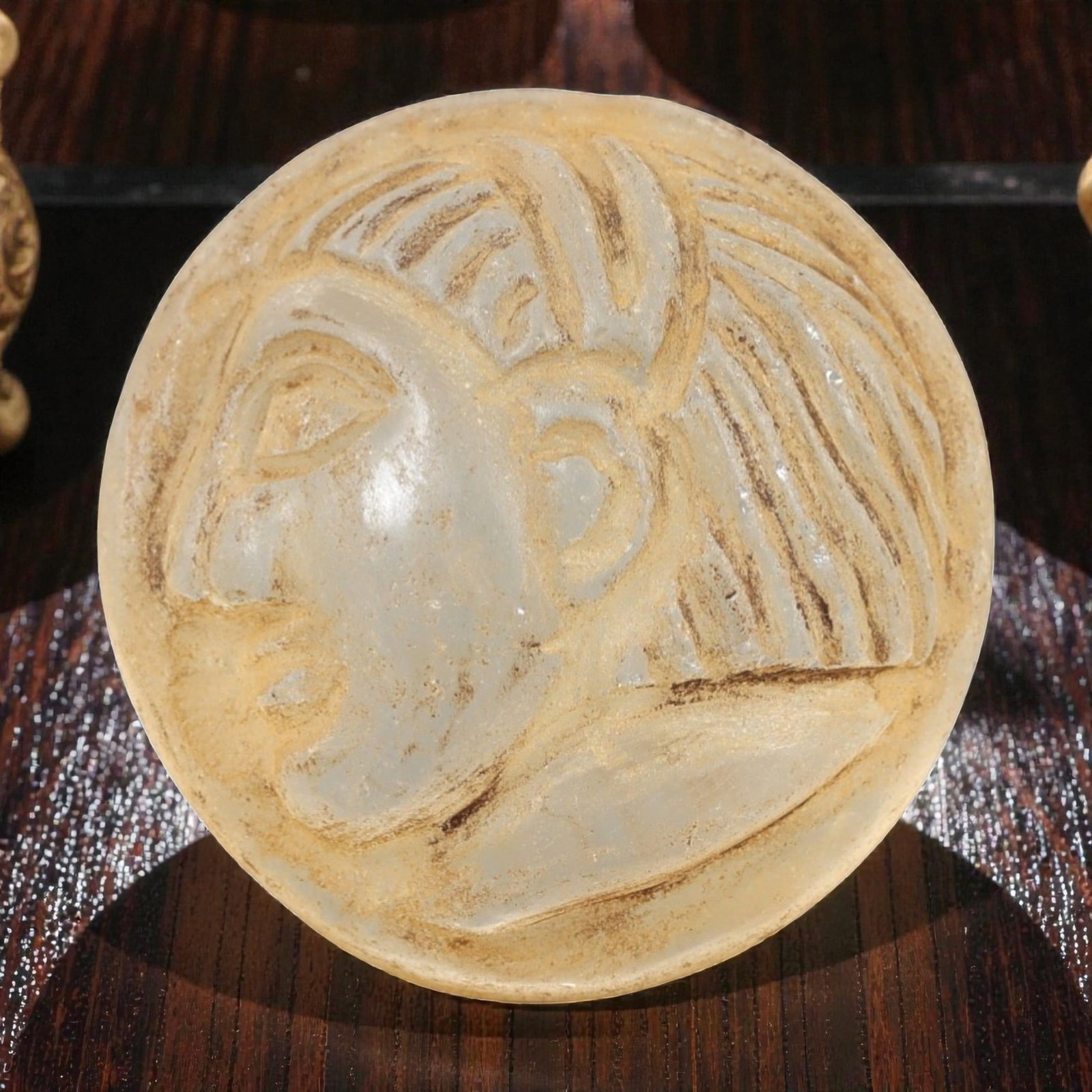 Ancient Glass Medieval Amulet - Near Eastern Relic, 90AL: This artifact is crafted from ancient glass, formed into a circular disc and carved in relief with a profile human head, featuring stylized linear hair patterns, defined facial features, and a distinc