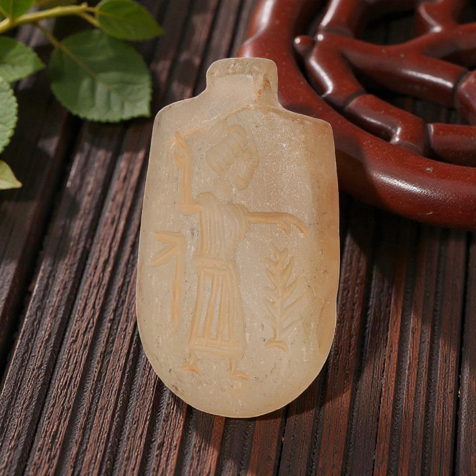 Ancient Sasanian Chalcedony Amulet Pendant, 59YD: This ancient amulet pendant is carved from translucent pale chalcedony, with a shield-shaped form and suspension lug at the top. The face features a deeply engraved intaglio depicting a standing figur