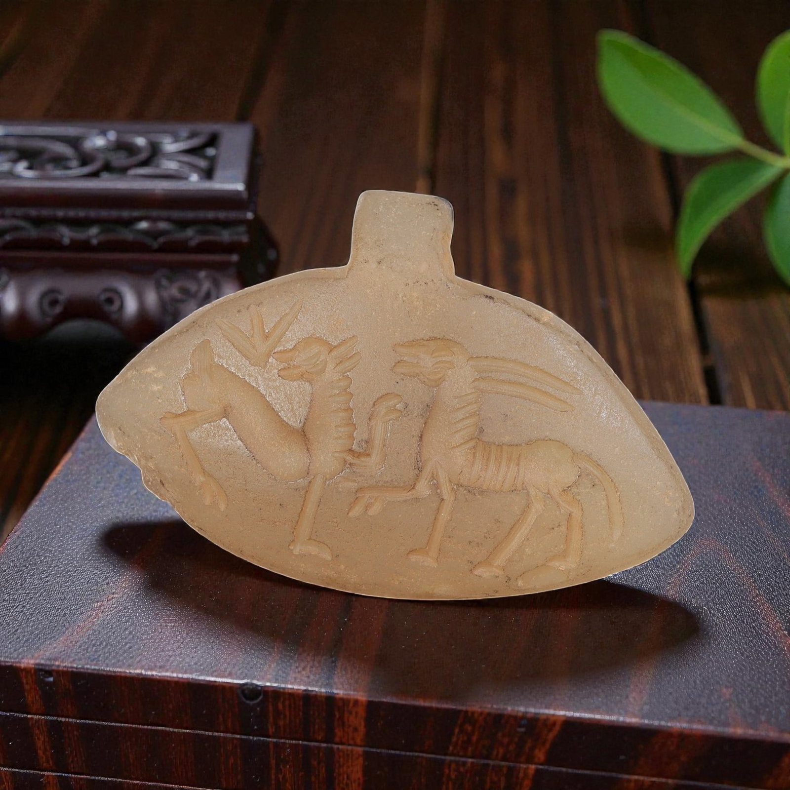 Ancient Sasanian Chalcedony Amulet Pendant, 54YD: This ancient amulet pendant is carved from translucent pale chalcedony, with a fan-shaped form and suspension lug at the top. The face features a deeply engraved intaglio depicting two stylized confro