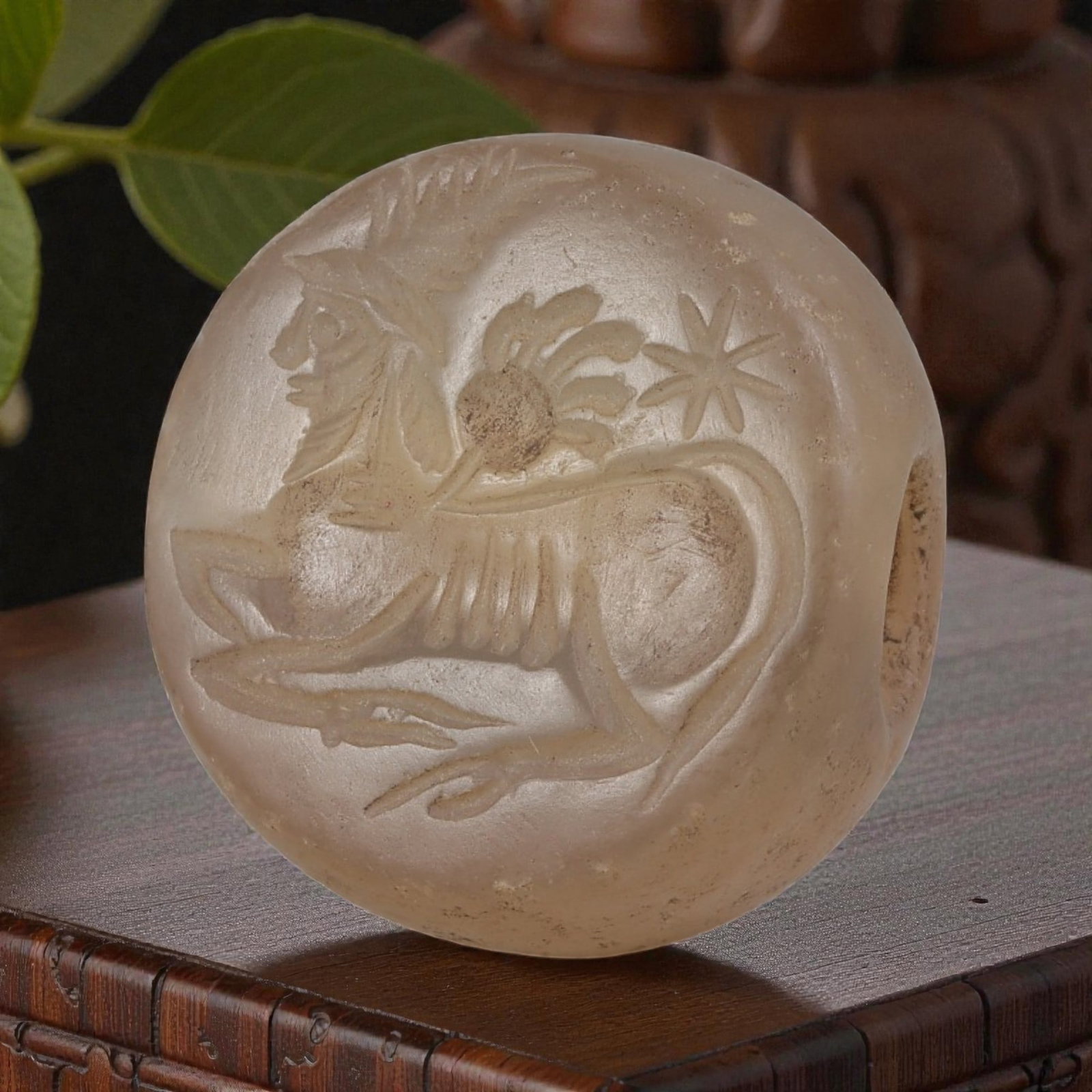 Ancient Sasanian Chalcedony Zoomorphic Stamp Seal, 76YD: This ancient stamp seal is carved from translucent chalcedony, featuring a domed, lenticular form with a central perforation for suspension. The flat face bears a finely engraved intaglio depicting a 