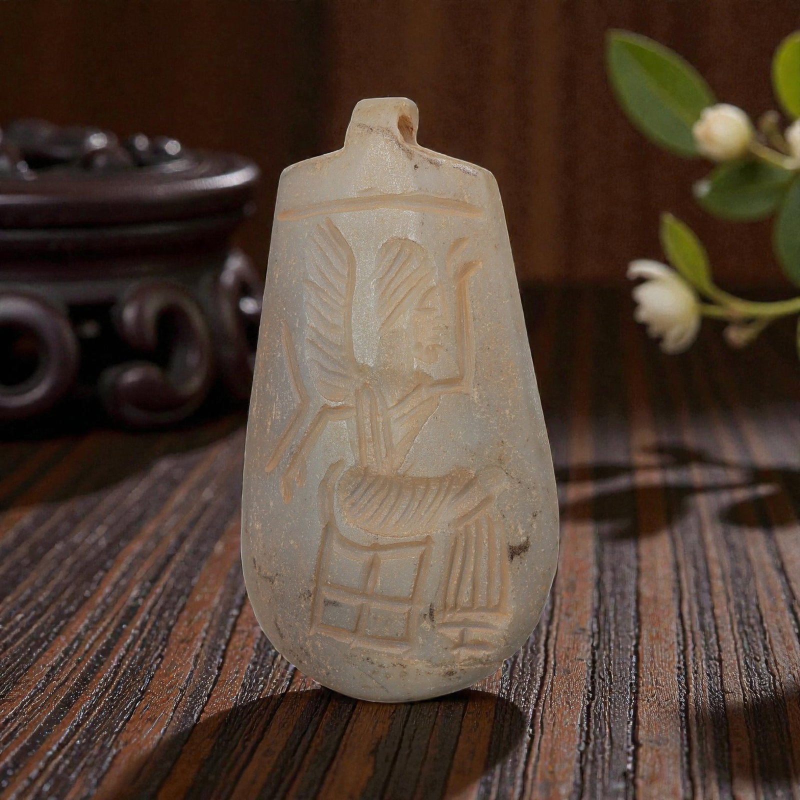 Ancient Sasanian Chalcedony Amulet Pendant, 57YD: This ancient amulet pendant is carved from translucent pale chalcedony, with a teardrop-shaped form and suspension lug at the top. The face features a deeply engraved intaglio depicting a seated winge