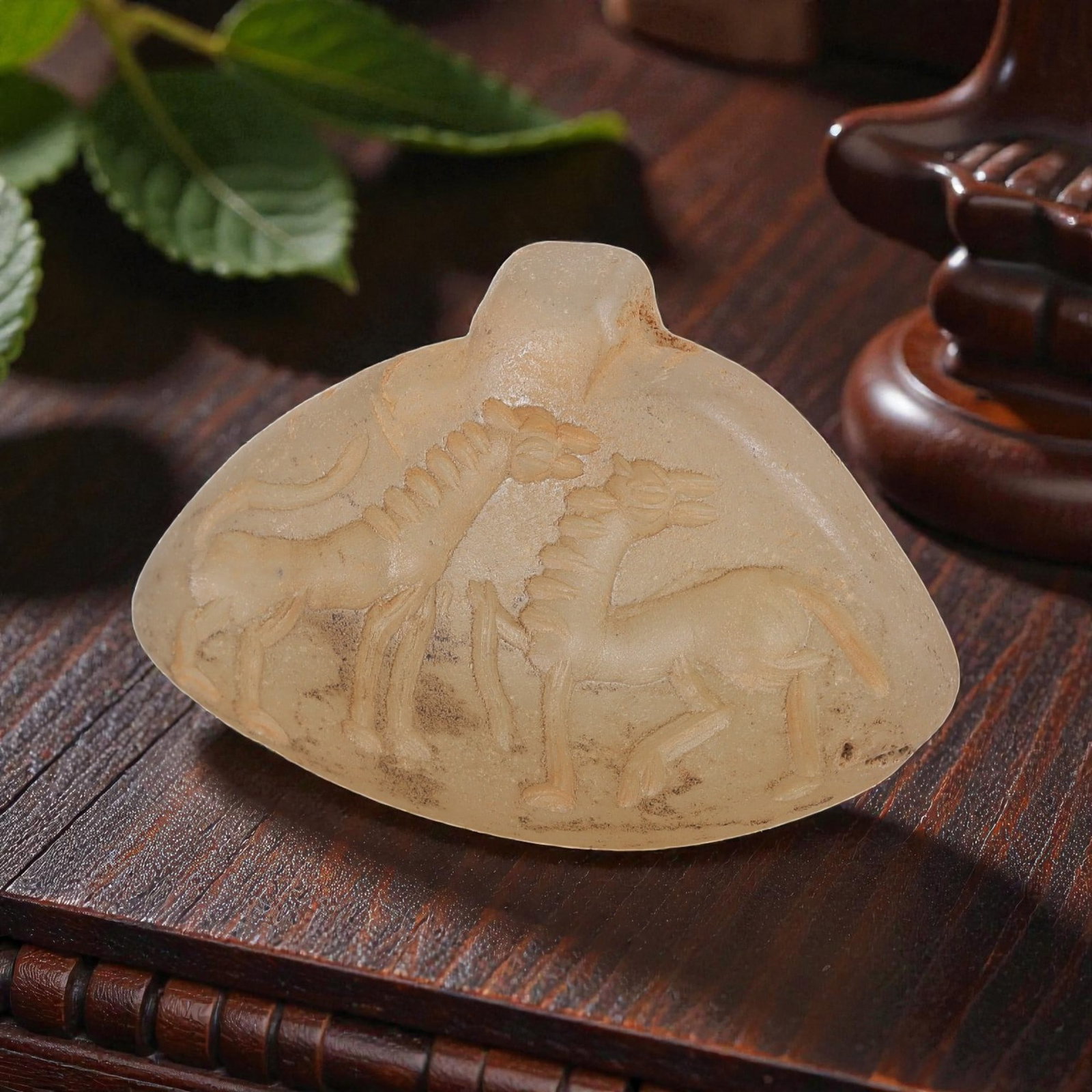 Ancient Sasanian Chalcedony Amulet Pendant, 50YD: This ancient amulet pendant is carved from translucent pale chalcedony, with a fan-shaped form and suspension lug at the top. The face features a deeply engraved intaglio depicting two stylized quadru