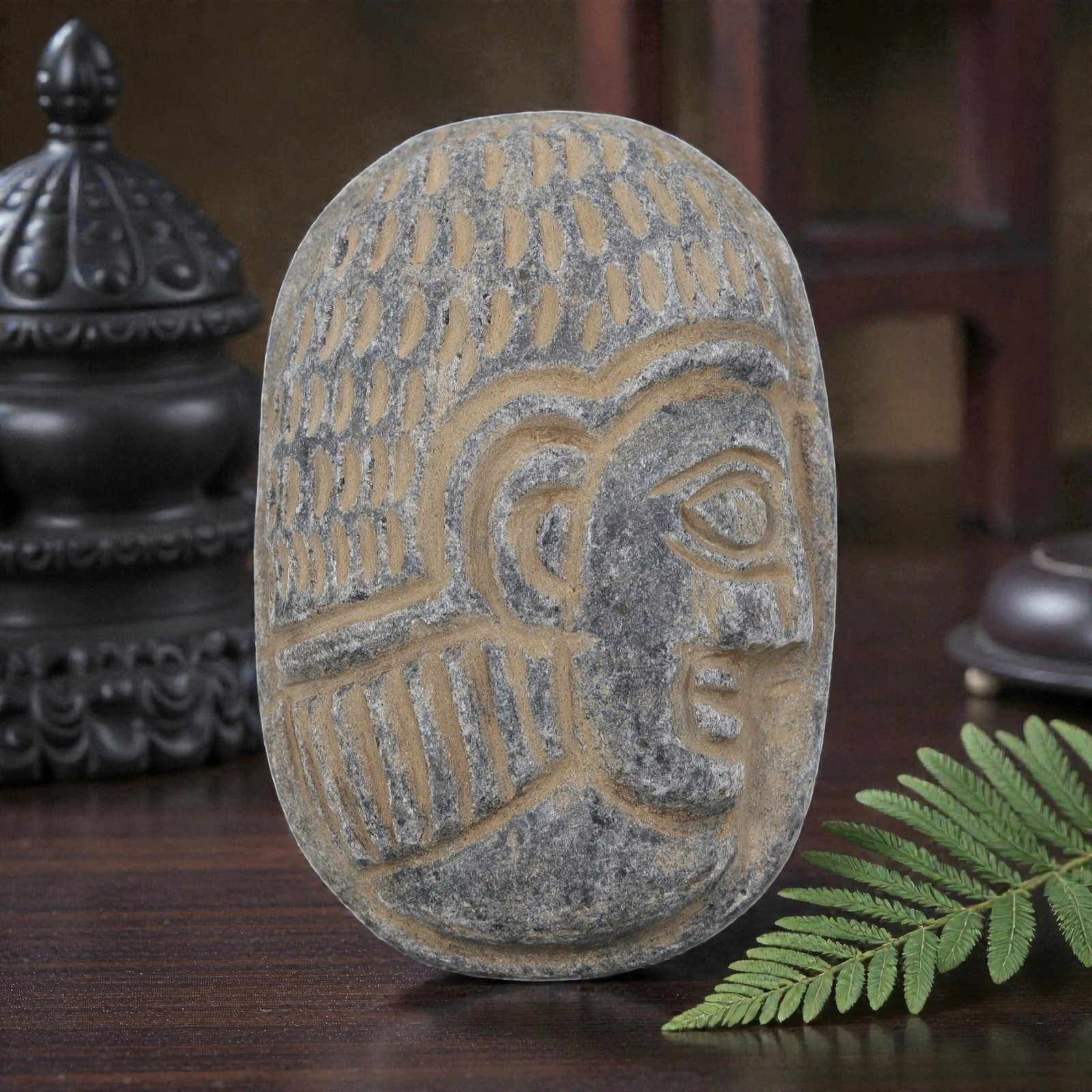 Antique Egyptian Schist Intaglio with Profile Head Motif, 33AP: Carved from dark grey schist, this oval intaglio depicts a stylized human head in profile, with incised dot patterns on the headdress and linear carvings defining the hairstyle and facial features. Ea