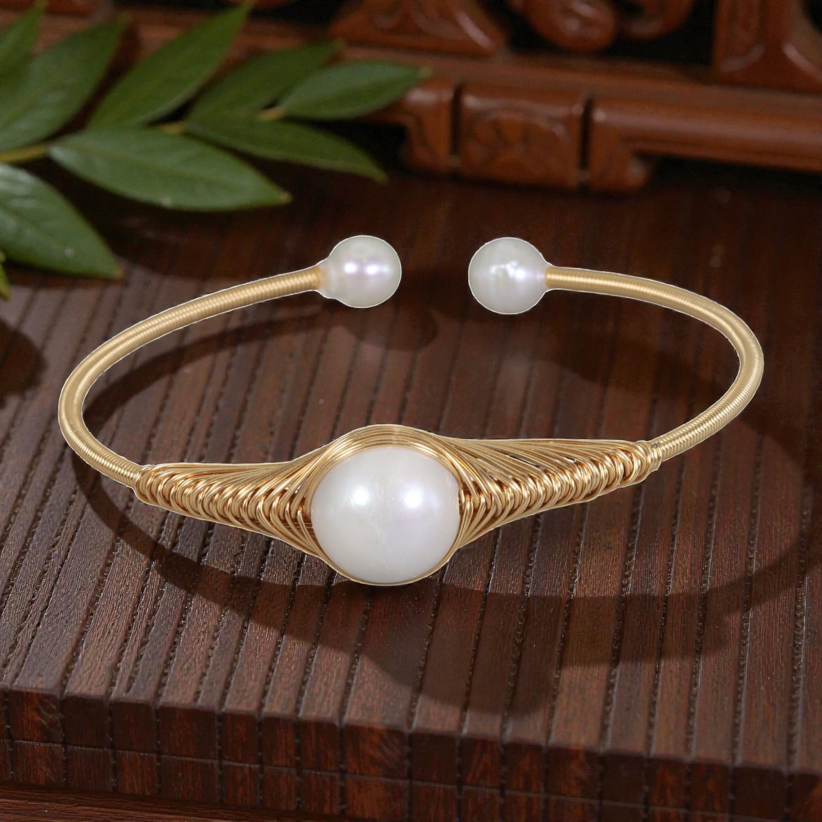 Natural Freshwater Pearl Gold Wire-Wrapped Open Cuff Bracelet, 23EB: A handcrafted open cuff bracelet made with gold-toned wire, intricately woven around a large round natural white freshwater pearl at the center. The wire is coiled in a decorative fan-like pattern aro