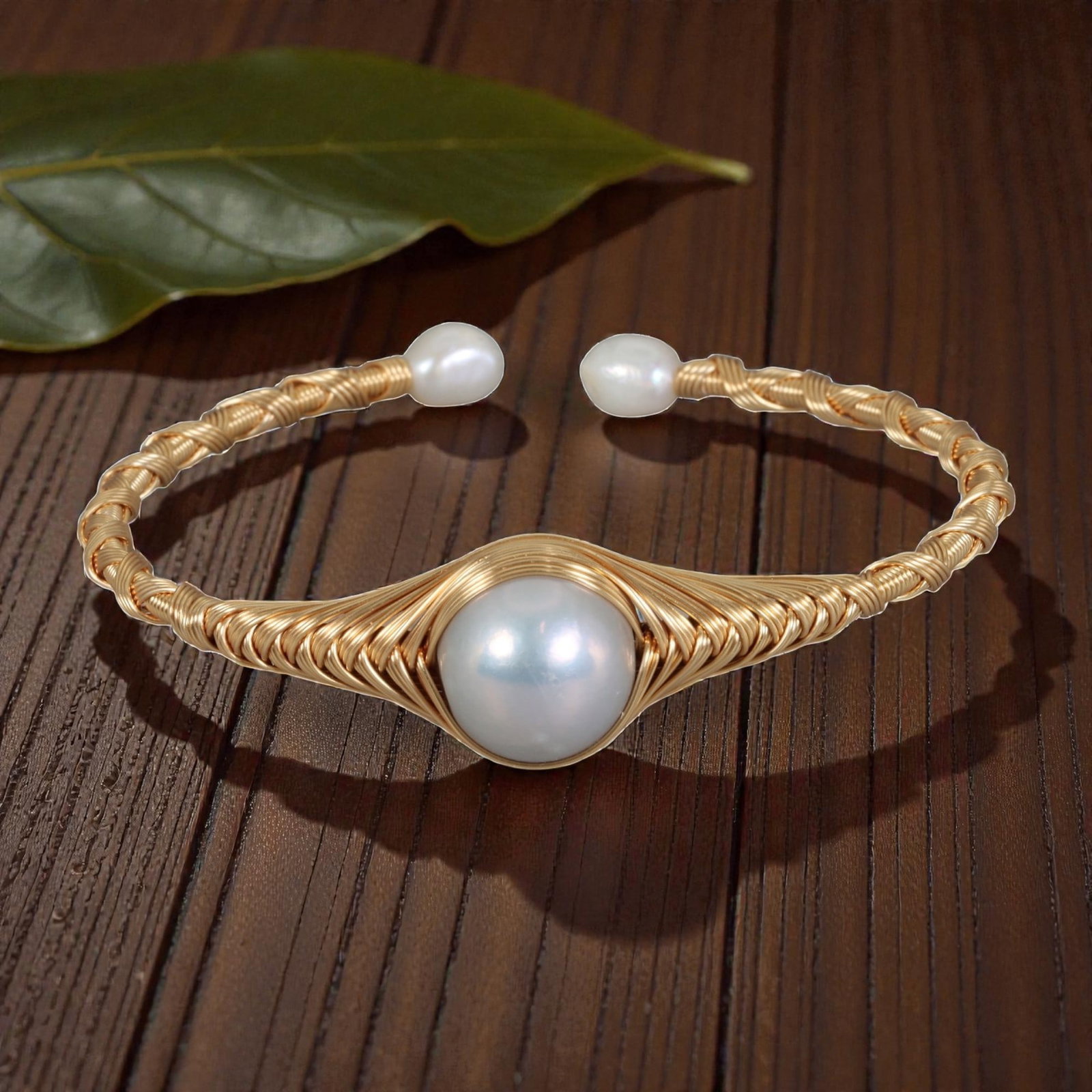 Natural Freshwater Pearl Gold Wire-Wrapped Open Cuff Bracelet, 21EB: A handcrafted open cuff bracelet made with gold-toned wire, intricately wrapped around a large, round natural freshwater pearl at the center. The wire is woven in a textured pattern around the central