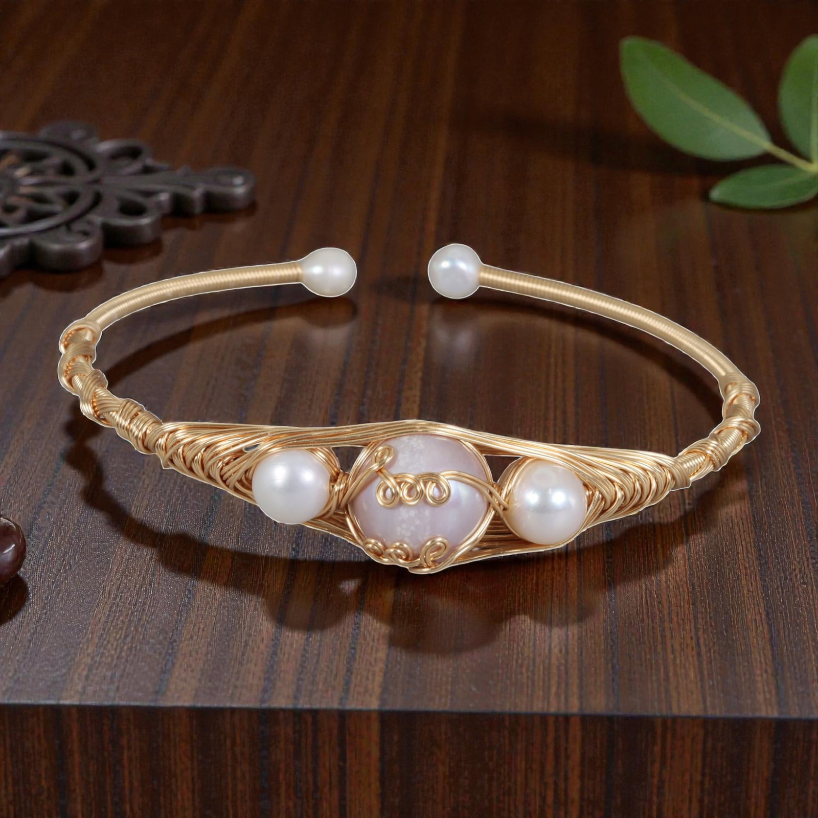 Natural Freshwater Pearl & Pink Stone Gold Wire-Wrapped Open Cuff Bracelet, 17EB: A handcrafted open cuff bracelet made with gold-toned wire, featuring a large pink stone at the center flanked by two round white freshwater pearls. The three stones are set within an intricately wove