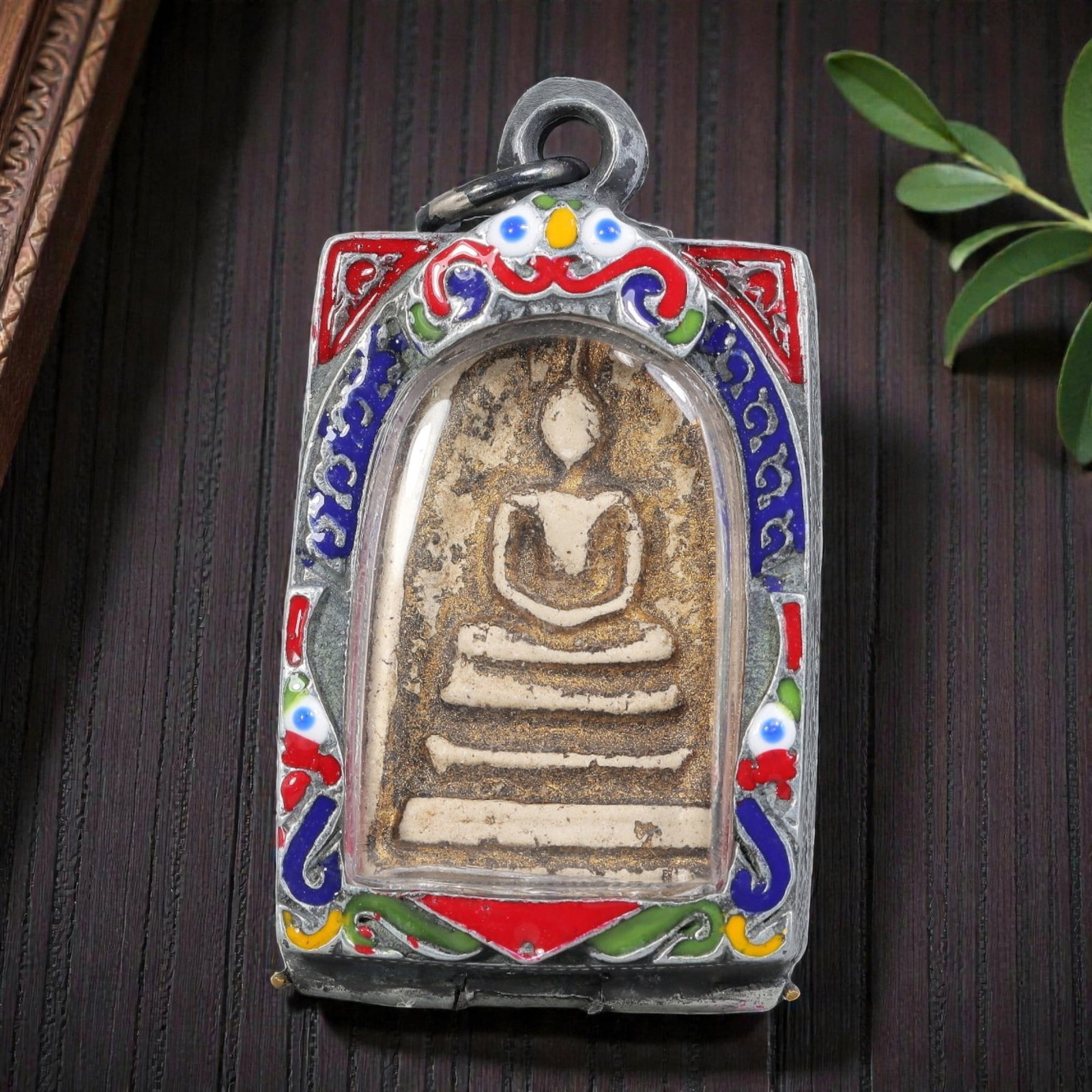 Thai Phra Somdej Amulet - Enamel Silver Tone Pendant, 60ZB: A Thai Buddhist Phra Somdej amulet featuring a seated Buddha figure on tiered bases, housed in a silver-tone metal casing with colorful enamel detailing. The glass-fronted enclosure protects the aged 