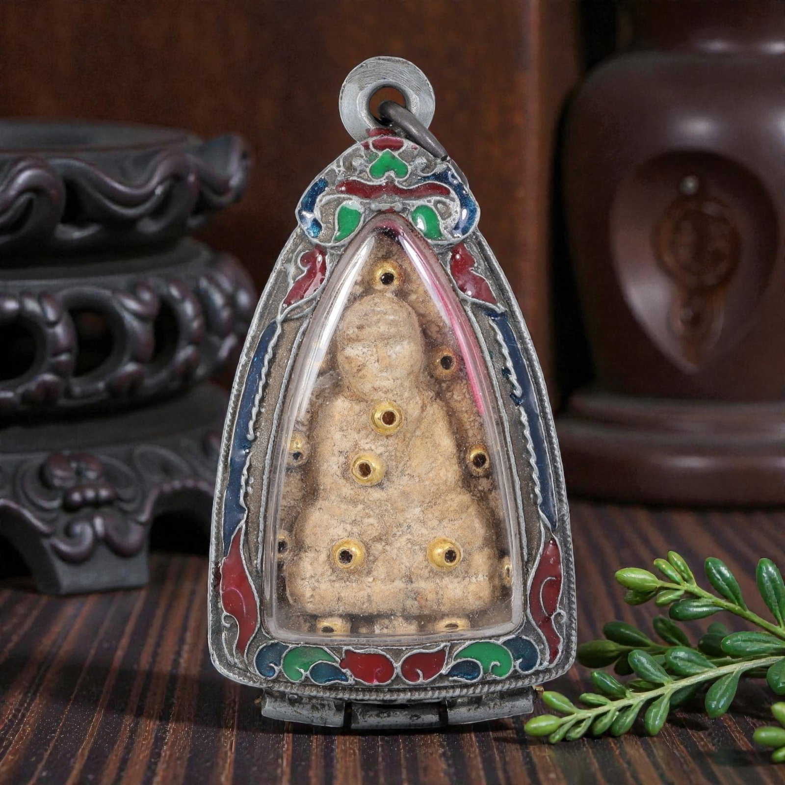 Thai Buddha Amulet - Enamel Silver Tone Pendant, 50AP: A Thai Buddhist amulet featuring a seated Buddha figure with inset gold-toned accents, housed in a silver-tone metal casing with colorful enamel detailing. The glass-fronted enclosure protects the age