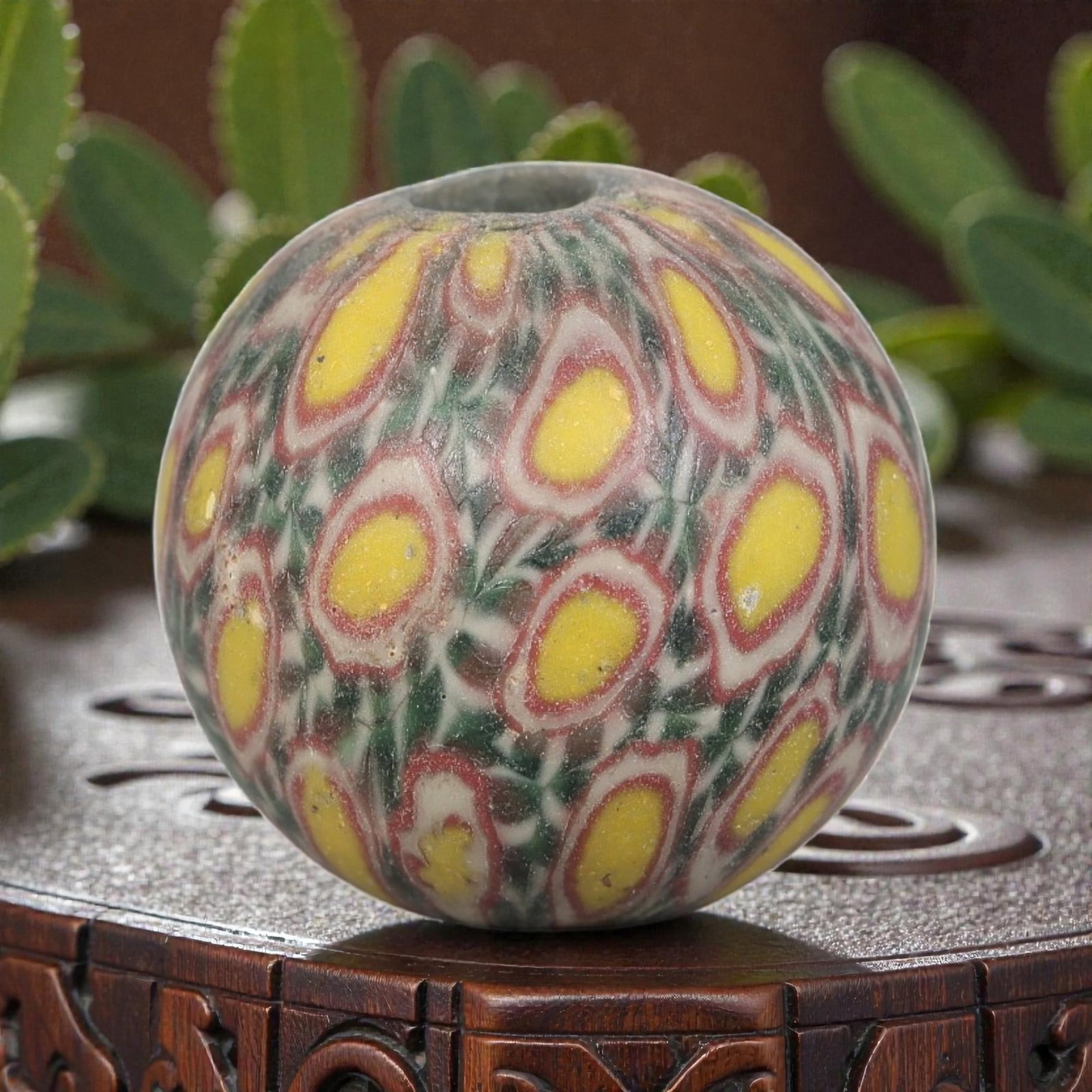 Antique Glass Bead - Islamic Jatim Yellow Peacock Eye Mosaic, 70AP: A spherical glass bead of Islamic Jatim type, crafted from polychrome mosaic glass. The surface features a repeating yellow peacock eye motif, with bright yellow ocelli framed by red and white borders