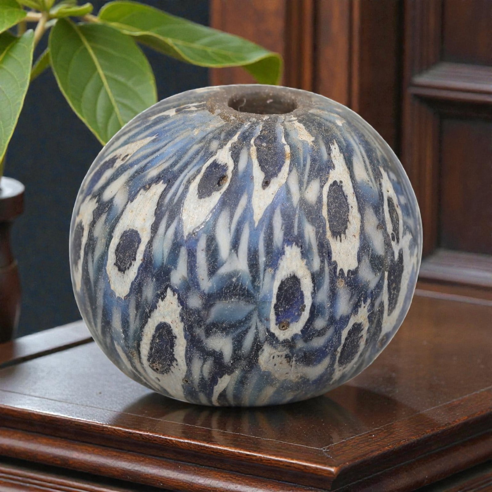 Antique Glass Bead - Islamic Jatim Indigo Peacock Eye Mosaic, 68AP: A spherical glass bead of Islamic Jatim type, crafted from polychrome mosaic glass. The surface features an intricate repeating indigo peacock eye motif, with layered white and deep blue ocelli patter