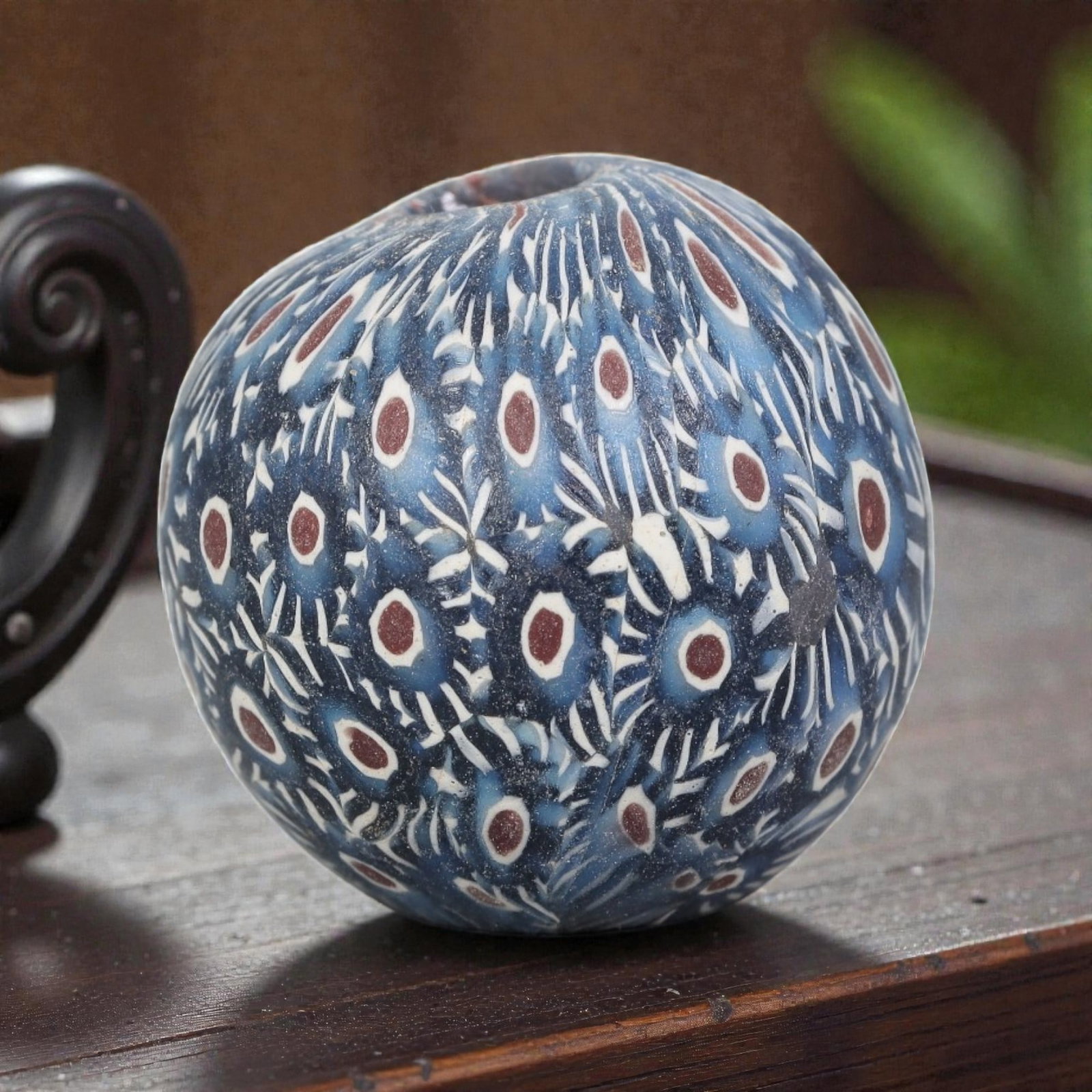 Antique Glass Bead - Islamic Jatim Peacock Eye Pattern, 66AP: A spherical glass bead of Islamic Jatim type, crafted from polychrome mosaic glass. The surface features an intricate peacock eye pattern, with repeating red-and-white ocelli motifs set against a deep