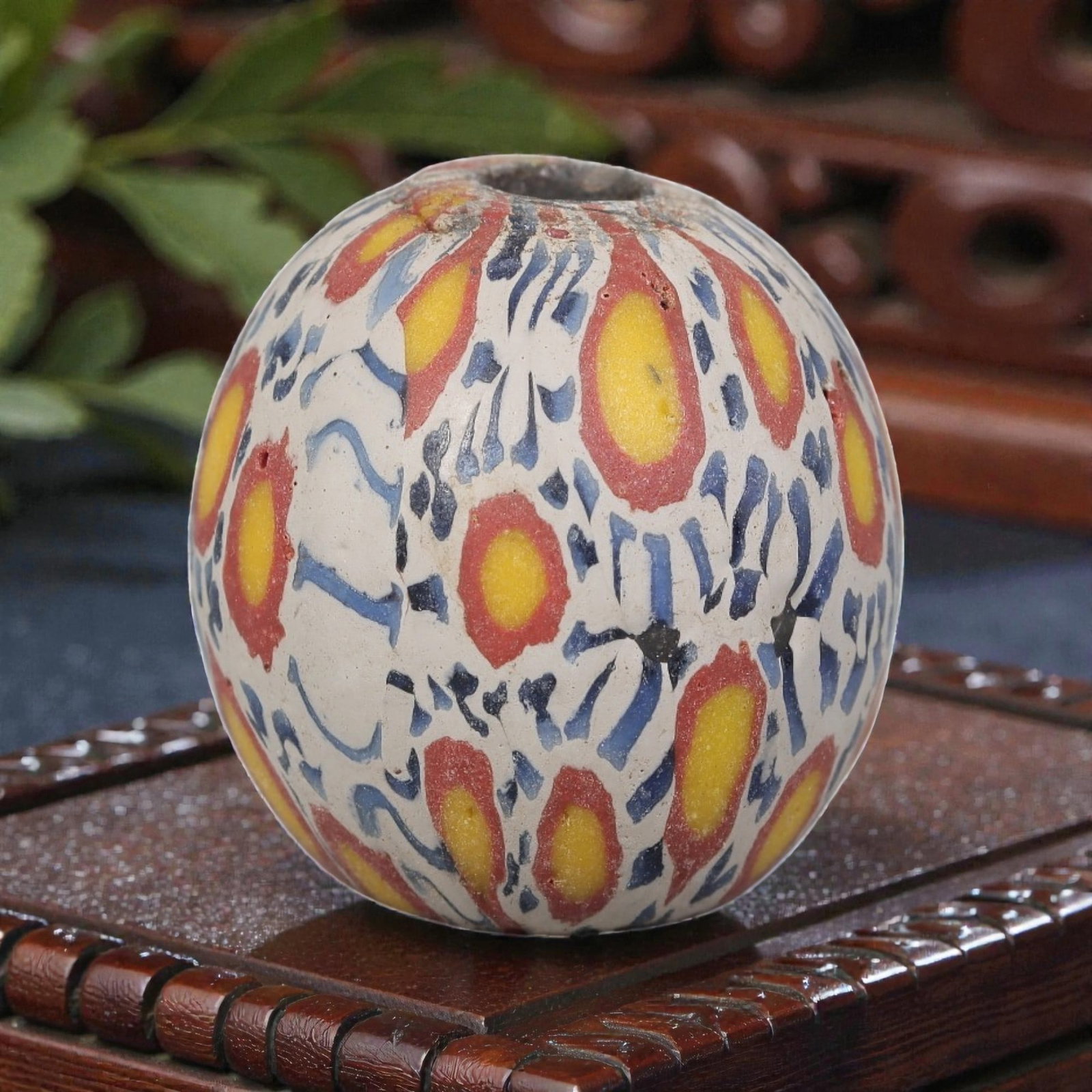Antique Glass Bead - Islamic Jatim Polychrome Eye Mosaic, 71AP: A spherical glass bead of Islamic Jatim type, crafted from polychrome mosaic glass. The surface features repeating eye motifs with yellow centers and red borders, set against a white ground interspers