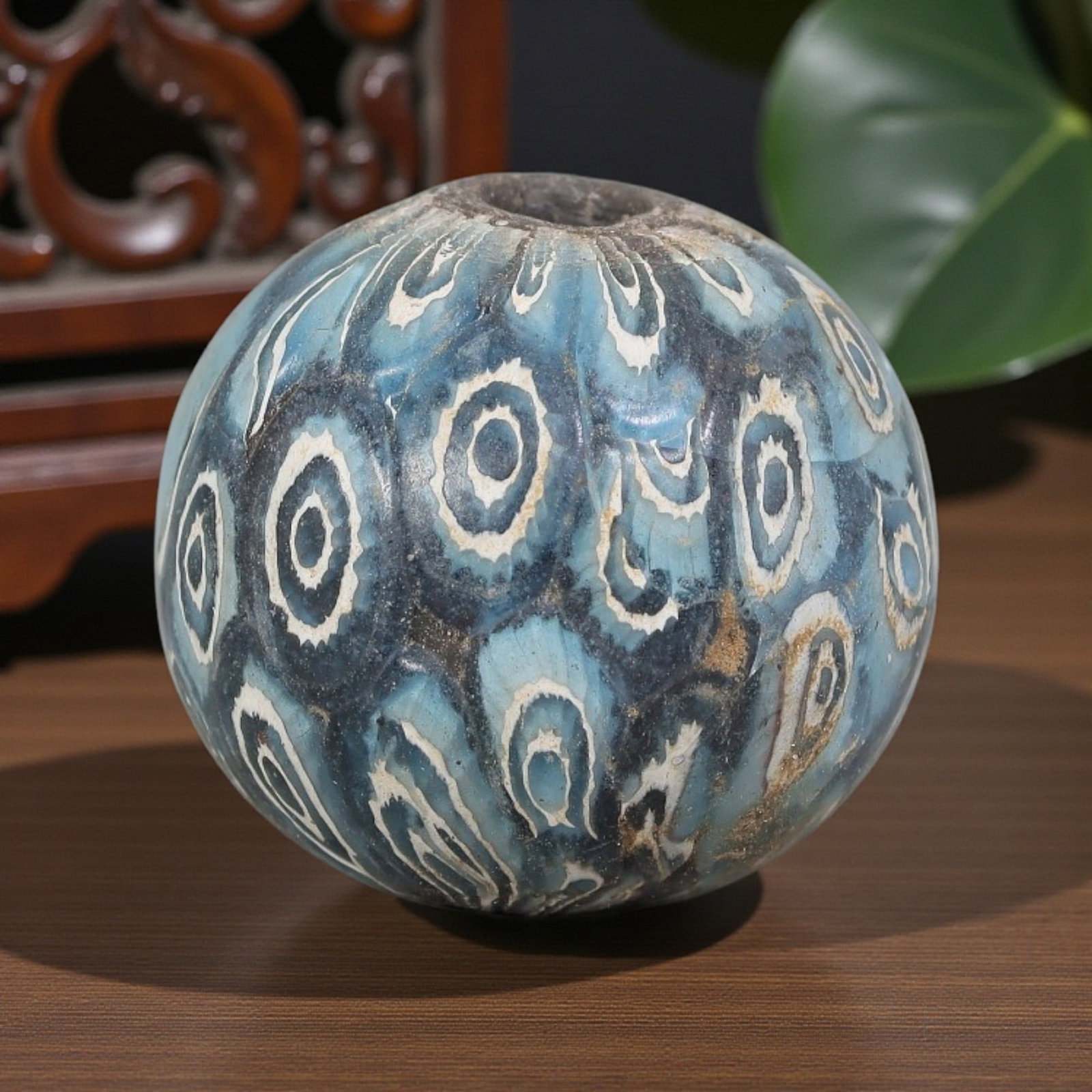 Antique Glass Bead - Islamic Jatim Blue-White Concentric Eye Mosaic, 61YH: A spherical glass bead of Islamic Jatim type, crafted from polychrome mosaic glass. The surface features repeating concentric eye motifs with dark centers framed by white rings, set against a layered 