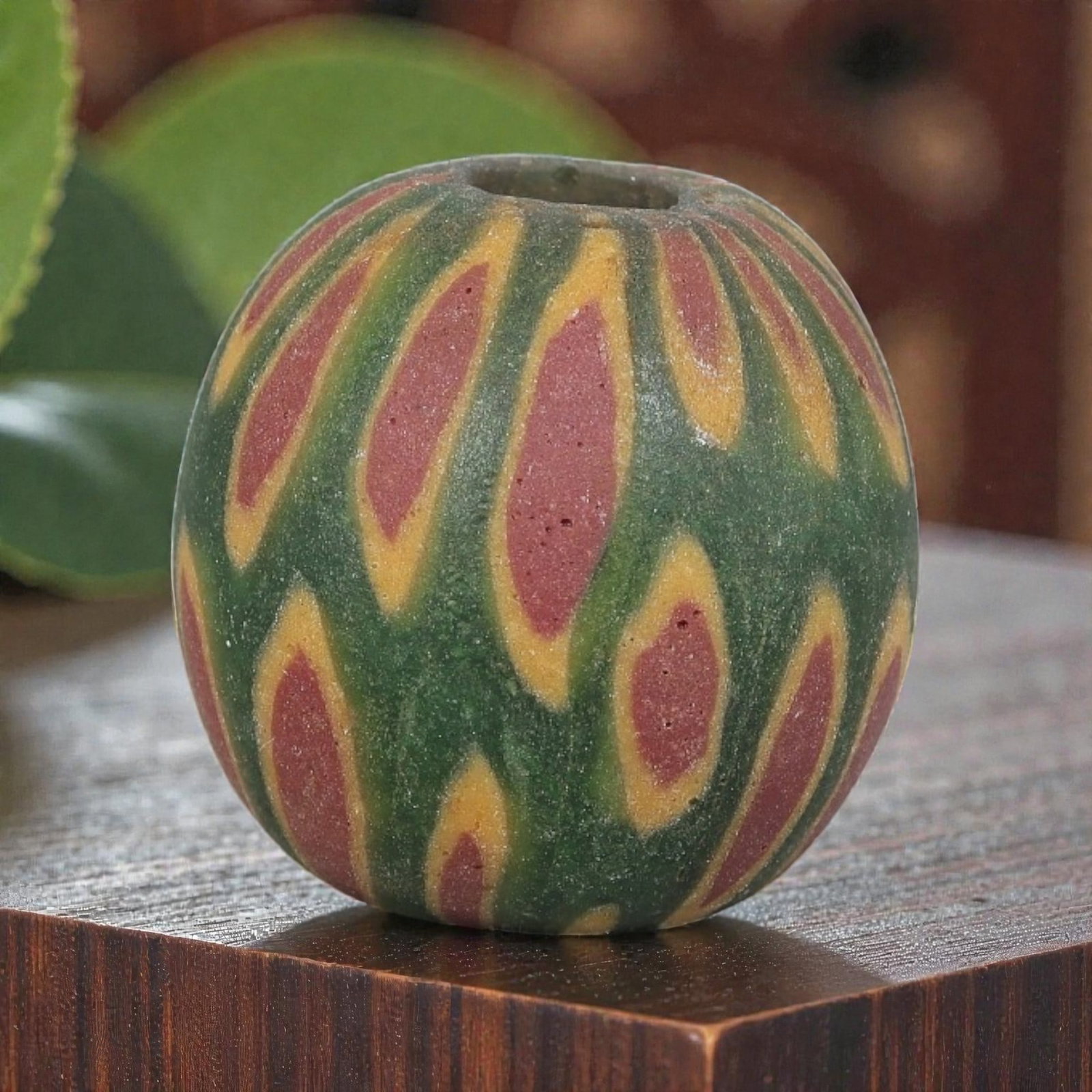 Antique Glass Bead - Islamic Jatim Green Ikat Feather Mosaic, 41YH: A spherical glass bead of Islamic Jatim type, crafted from polychrome mosaic glass. The surface features repeating elongated motifs with reddish centers framed by golden-yellow borders, set against a 