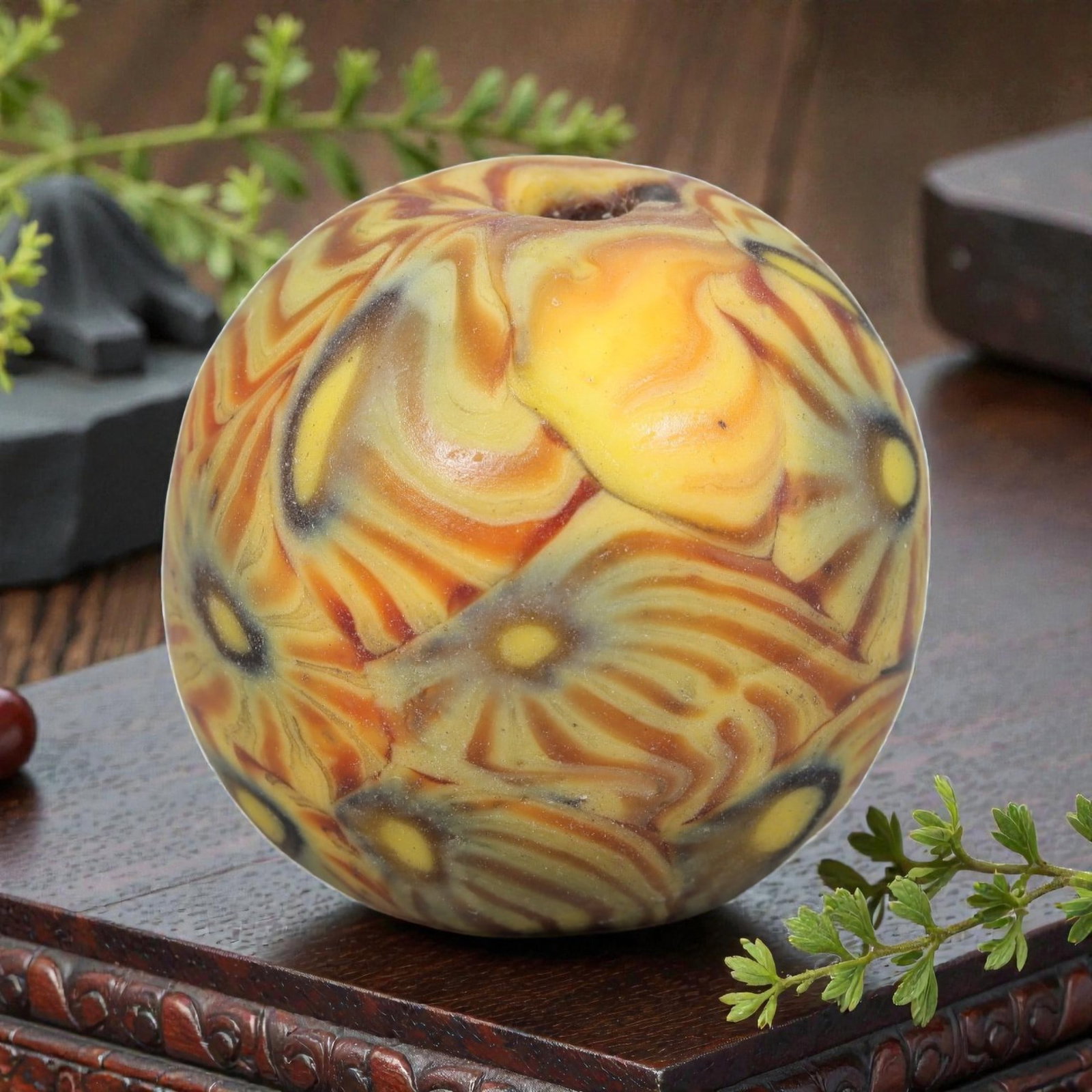 Antique Glass Bead - Islamic Jatim Marigold Swirl Mosaic, 58AP: A spherical glass bead of Islamic Jatim type, crafted from polychrome mosaic glass. The surface features a flowing marigold swirl motif, with warm yellow, orange, and cream tones blending into stylize