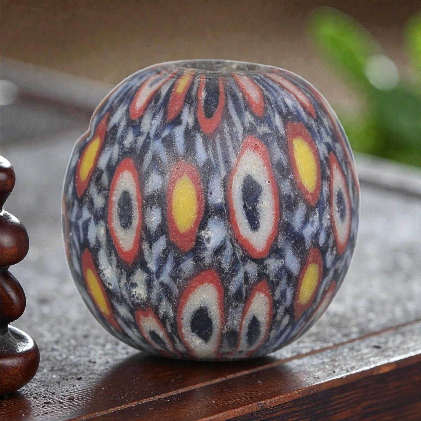 Antique Glass Bead - Islamic Jatim Multicolor Eye Mosaic, 45YH: A spherical glass bead of Islamic Jatim type, crafted from polychrome mosaic glass. The surface features repeating eye motifs in two distinct color schemes: one with dark centers framed by white rings