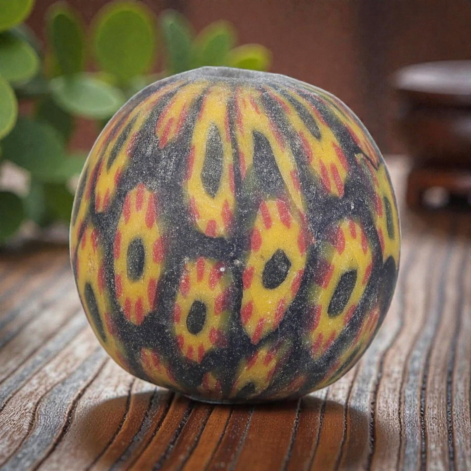 Antique Glass Bead - Islamic Jatim Yellow-Red Eye Mosaic, 71YH: A spherical glass bead of Islamic Jatim type, crafted from polychrome mosaic glass. The surface features repeating eye motifs with dark centers, framed by vibrant yellow and accented with red details,